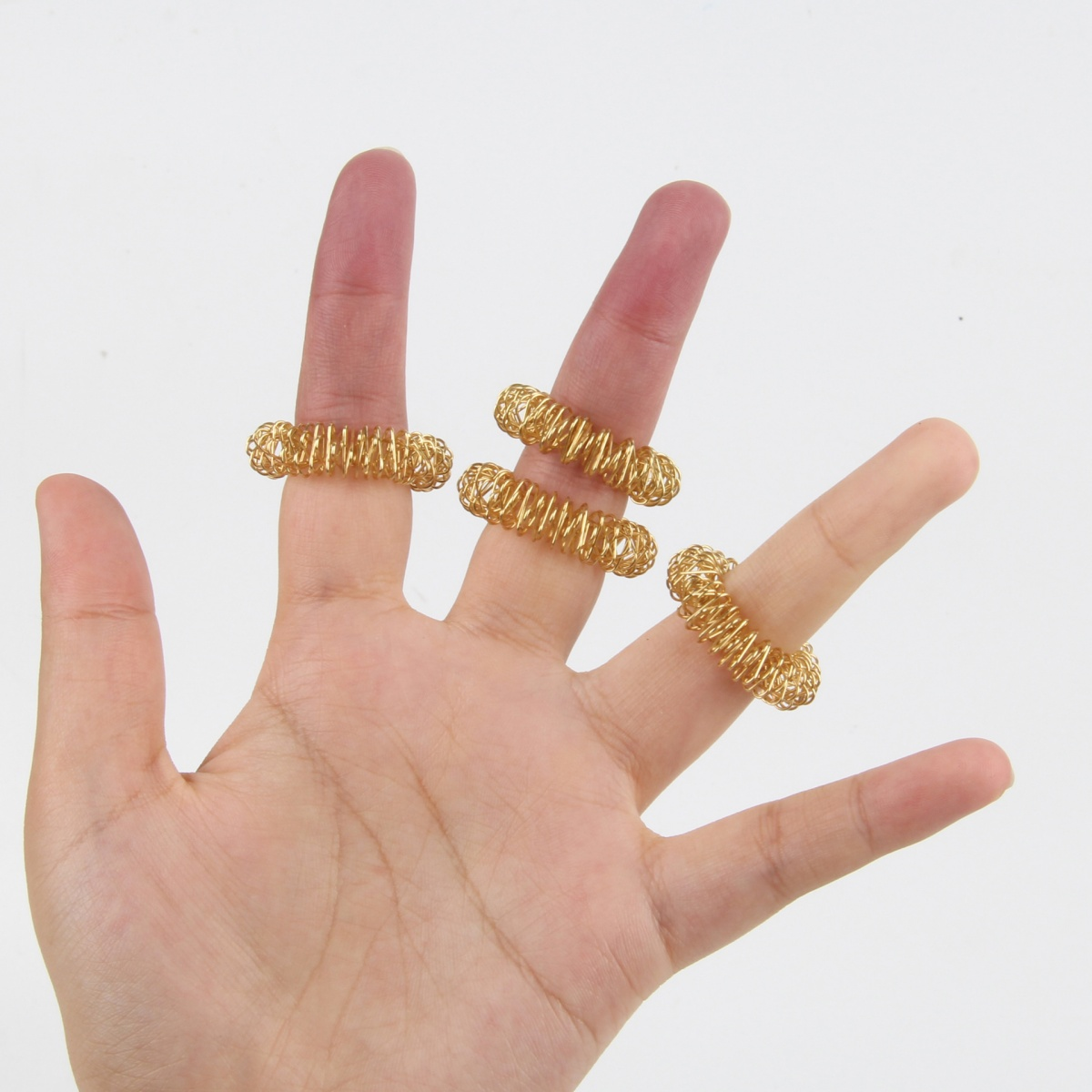 Hand mit vier goldenen Fingerringen. Ringe sind gewickelt und um die Finger gewickelt.