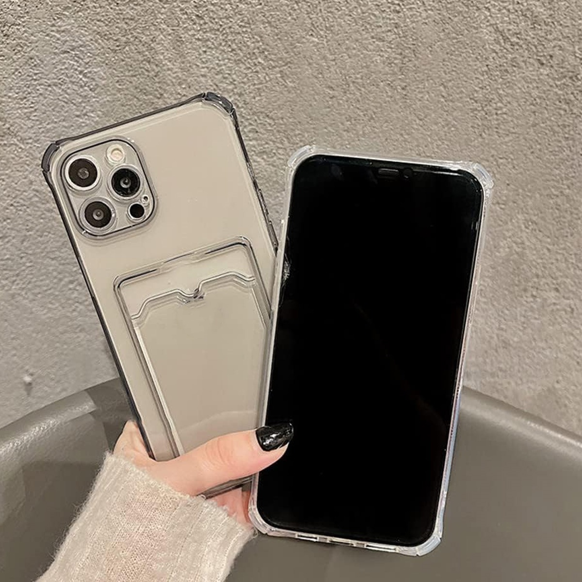 Ein Telefon und eine transparente Handyhülle mit Kartenfach. Hand einer Frau hält beides.