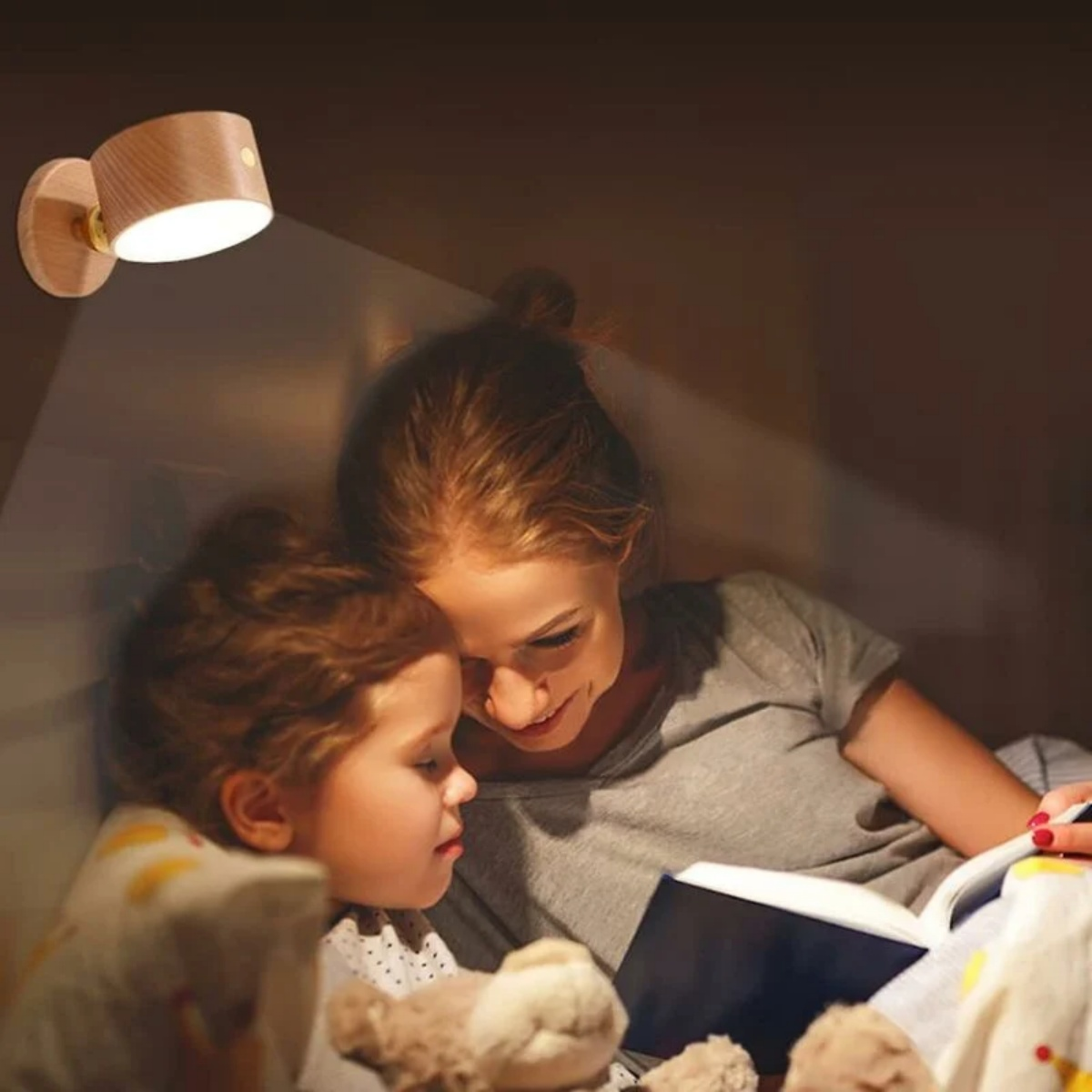 Eine Frau und ein Kind lesen unter einer hölzernen Wandlampe.