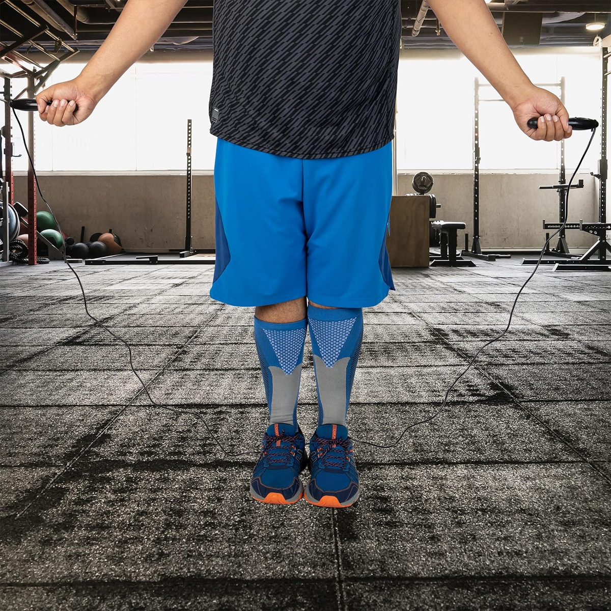 Eine Person springt in einem Fitnessstudio Seil, bekleidet mit Sportkleidung.