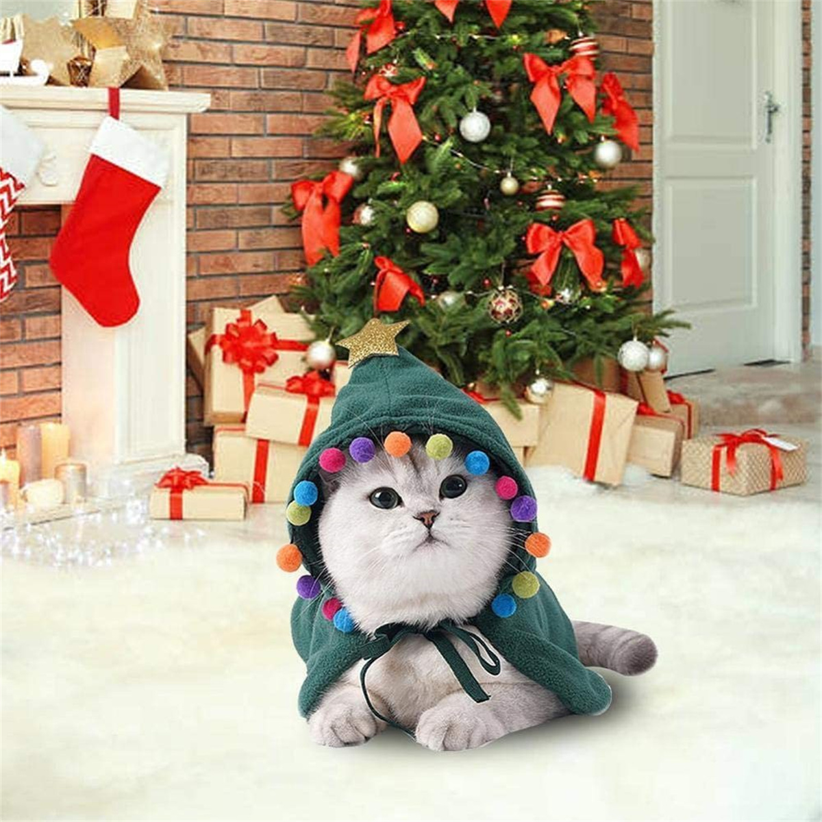 Eine Katze in einem Weihnachtsbaumkostüm sitzt vor einem geschmückten Weihnachtsbaum und einem Kamin mit einem Strumpf.