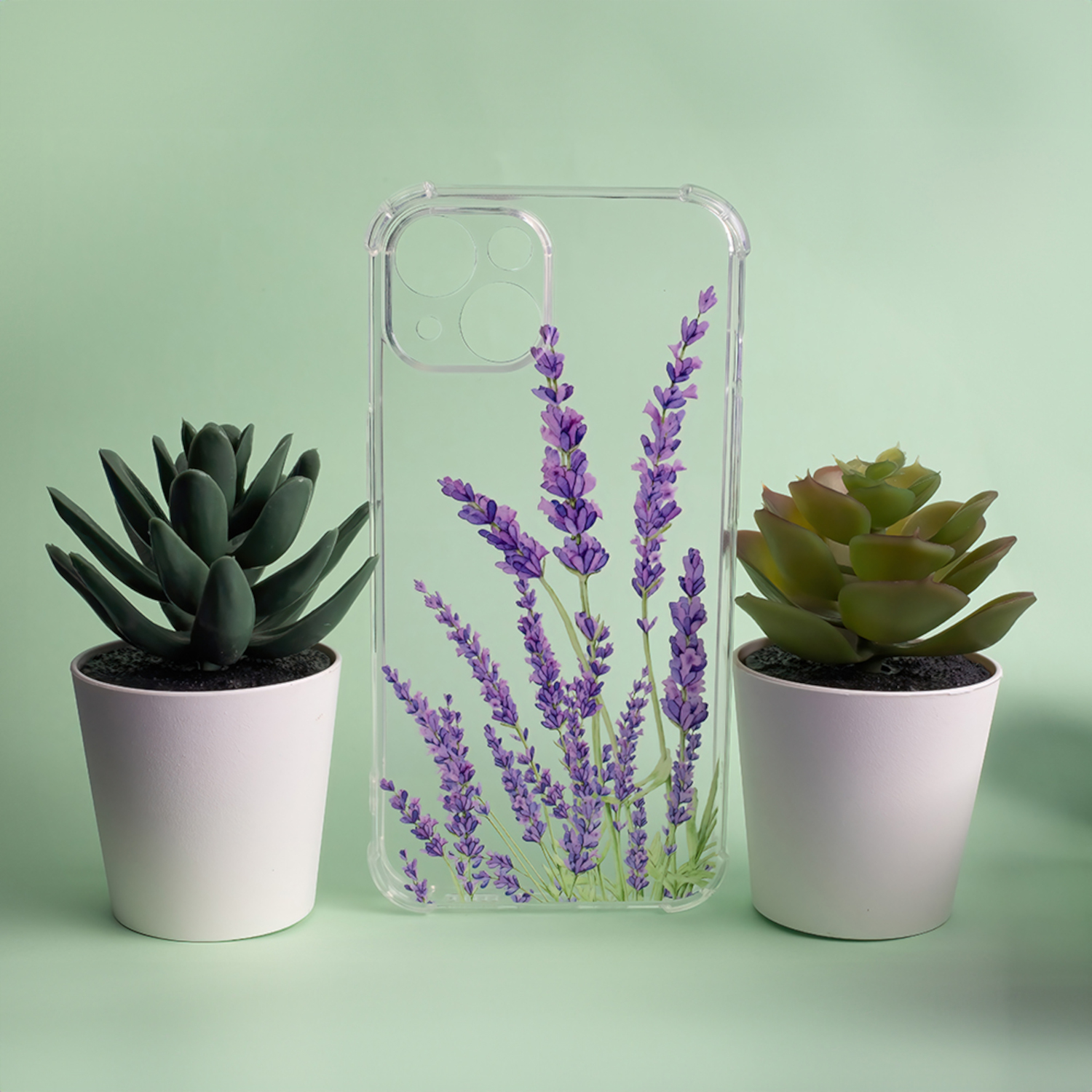 Eine transparente Handyhülle mit Lavendel-Blumendesign, die zwischen zwei Topf-Sukkulenten steht.