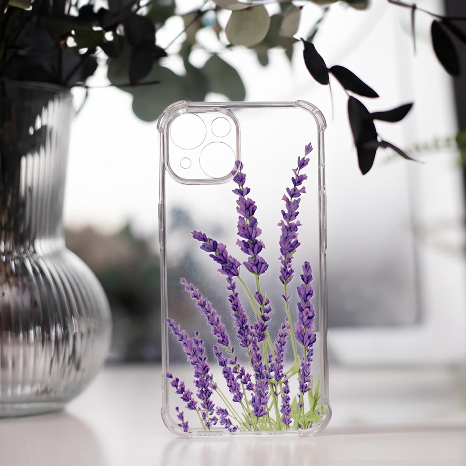 Transparente Handyhülle mit Lavendelblüten. Die Hülle liegt auf einer weißen Oberfläche.
