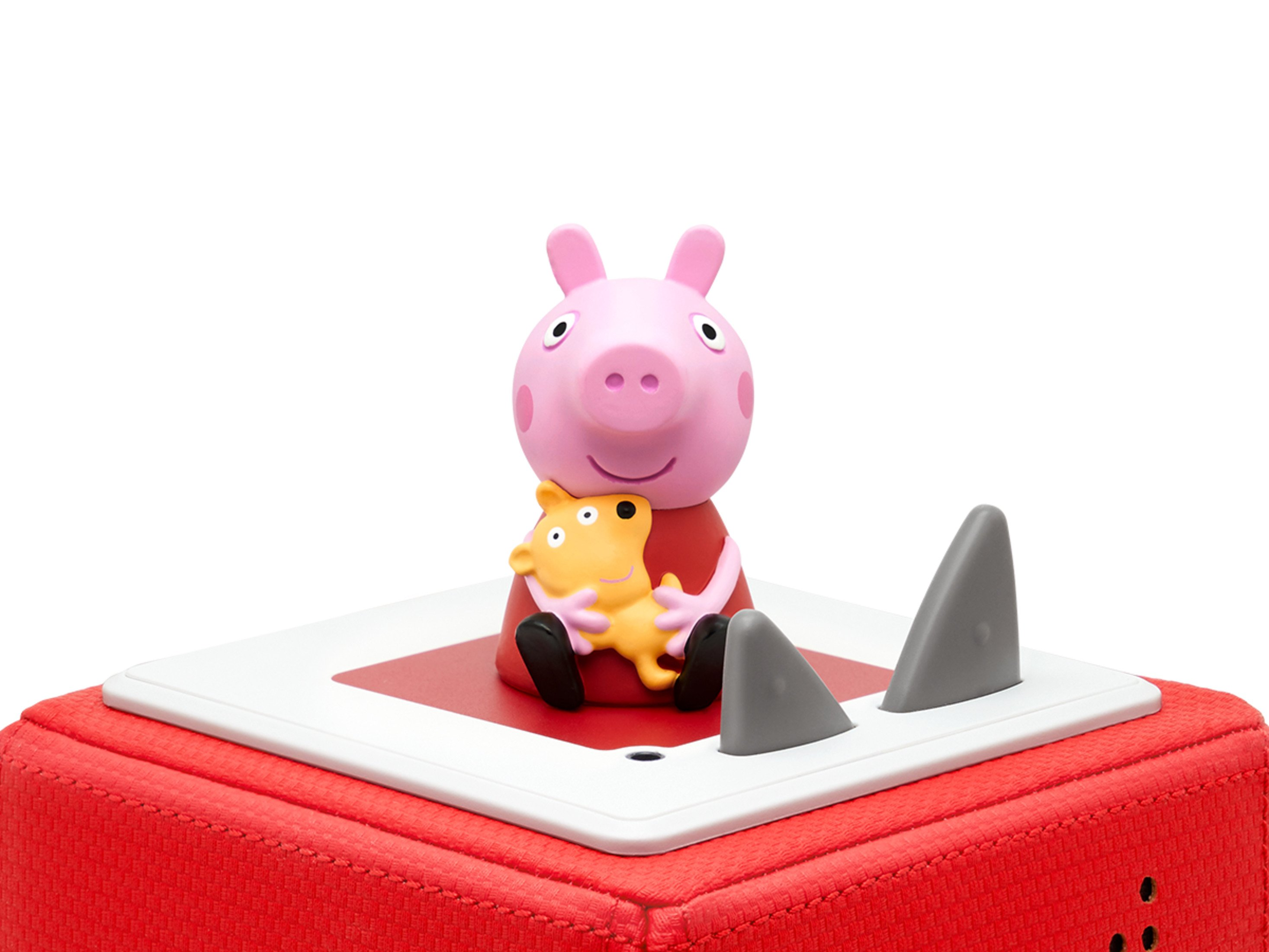 Peppa Wutz Spielzeug auf roter Box mit zwei grauen Flossen. Weißer Hintergrund.