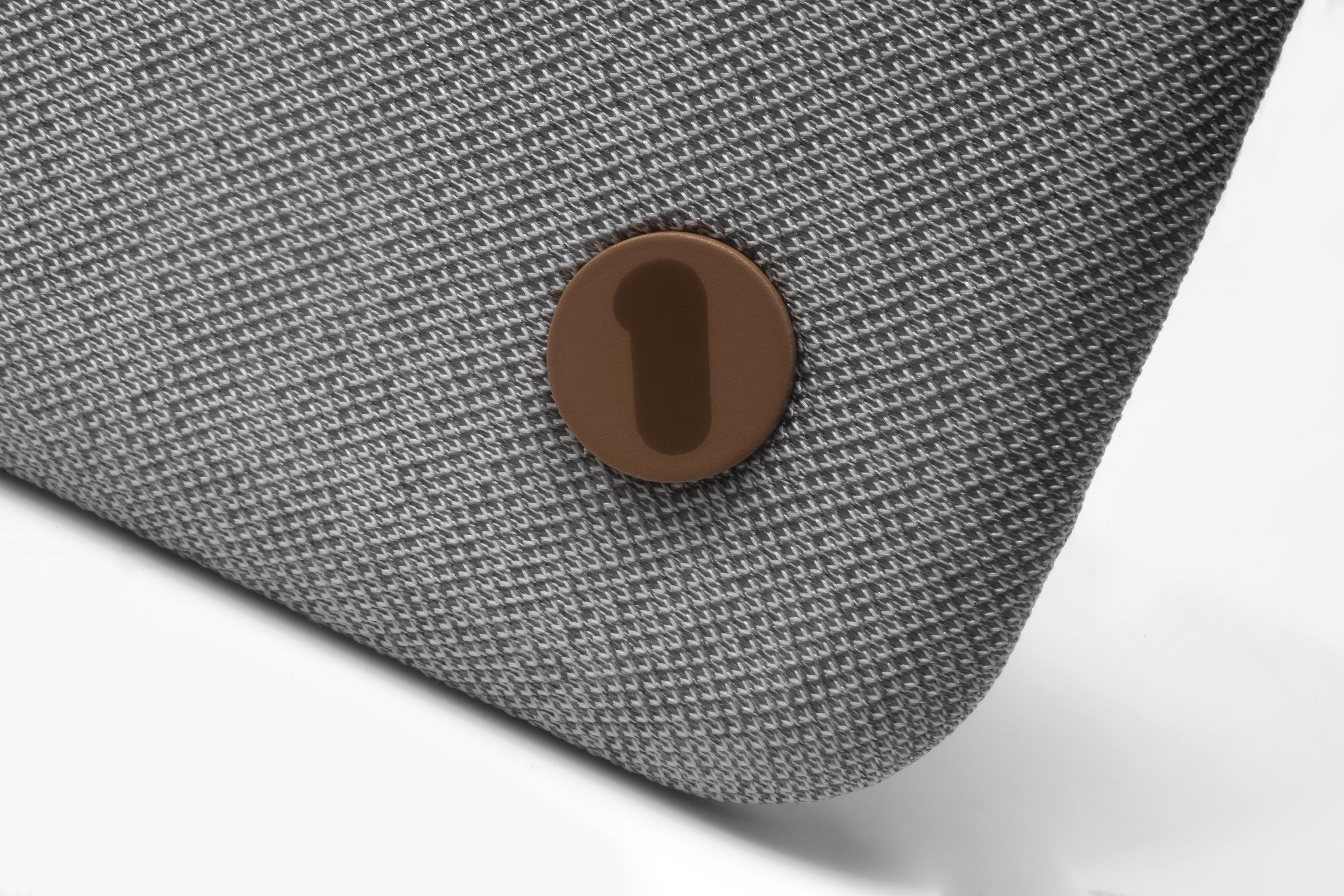 Fragment szarej tkaniny z przyszytym brązowym guzikiem z numerem 1.