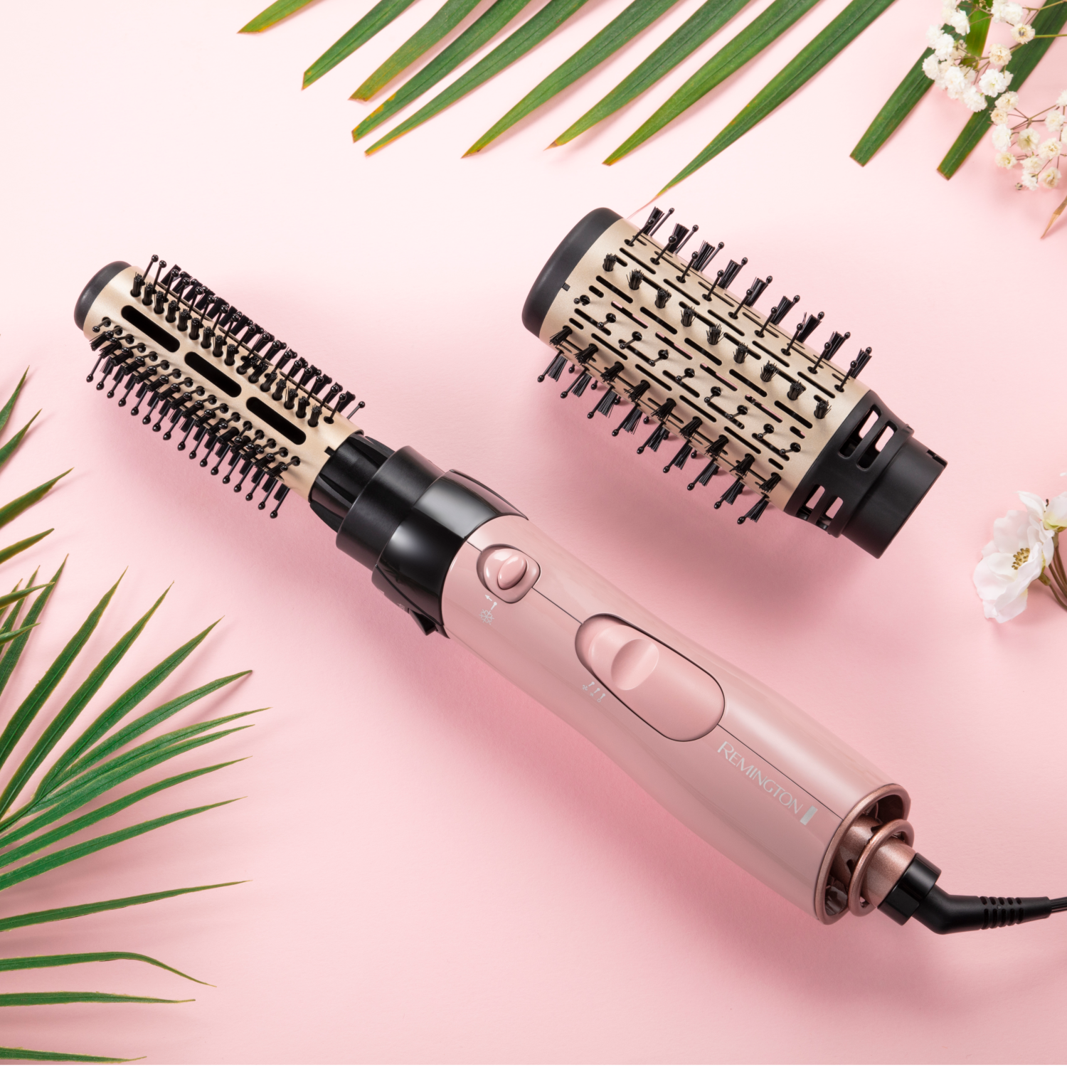 Strumento per lo styling dei capelli con due testine intercambiabili su sfondo rosa.