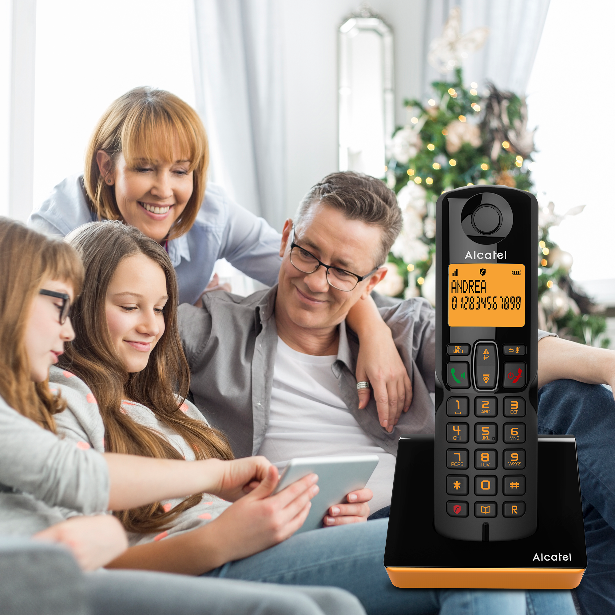 Famille de quatre personnes regardant une tablette, avec un téléphone sans fil au premier plan.