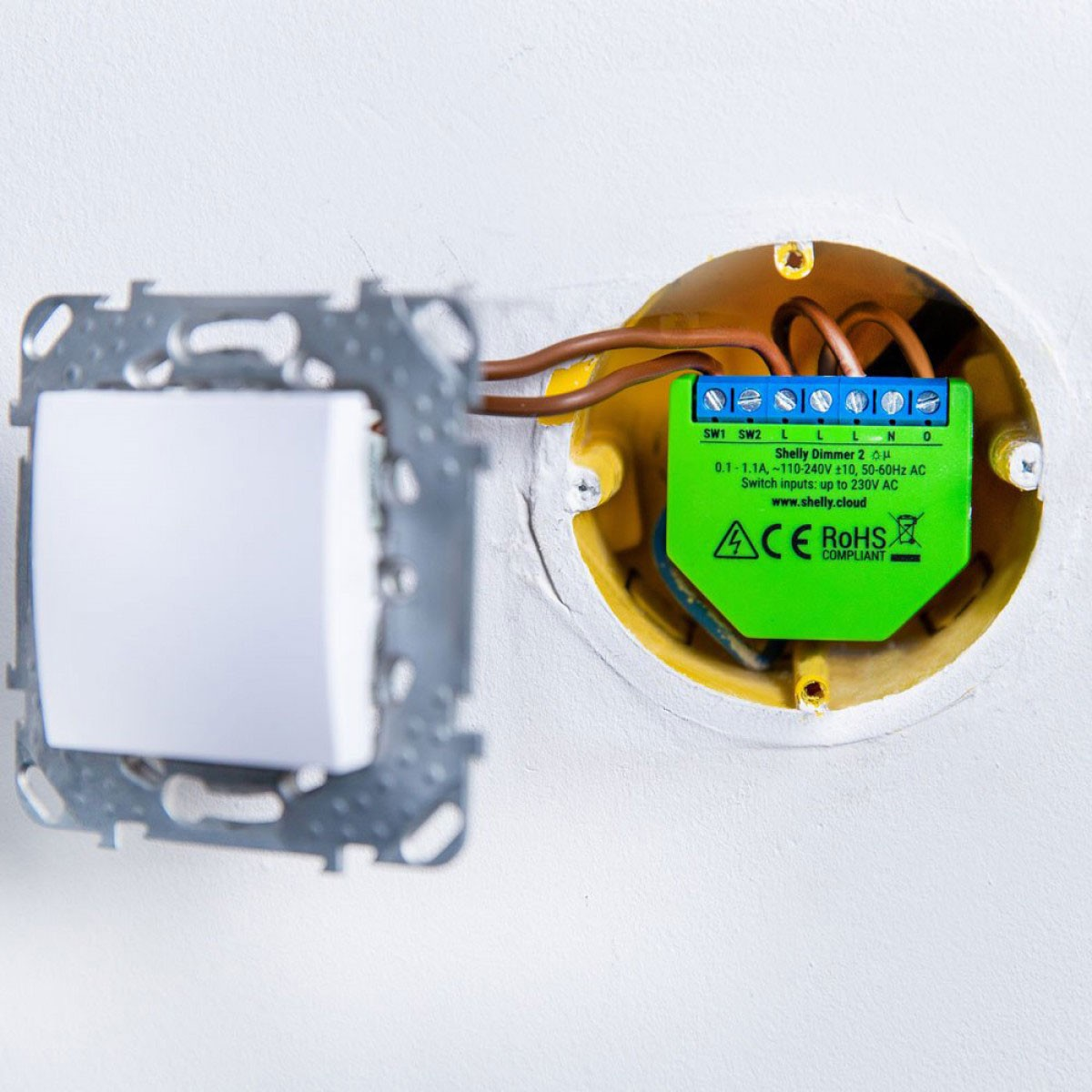 Componente eléctrico verde en pared, con cableado y un interruptor.