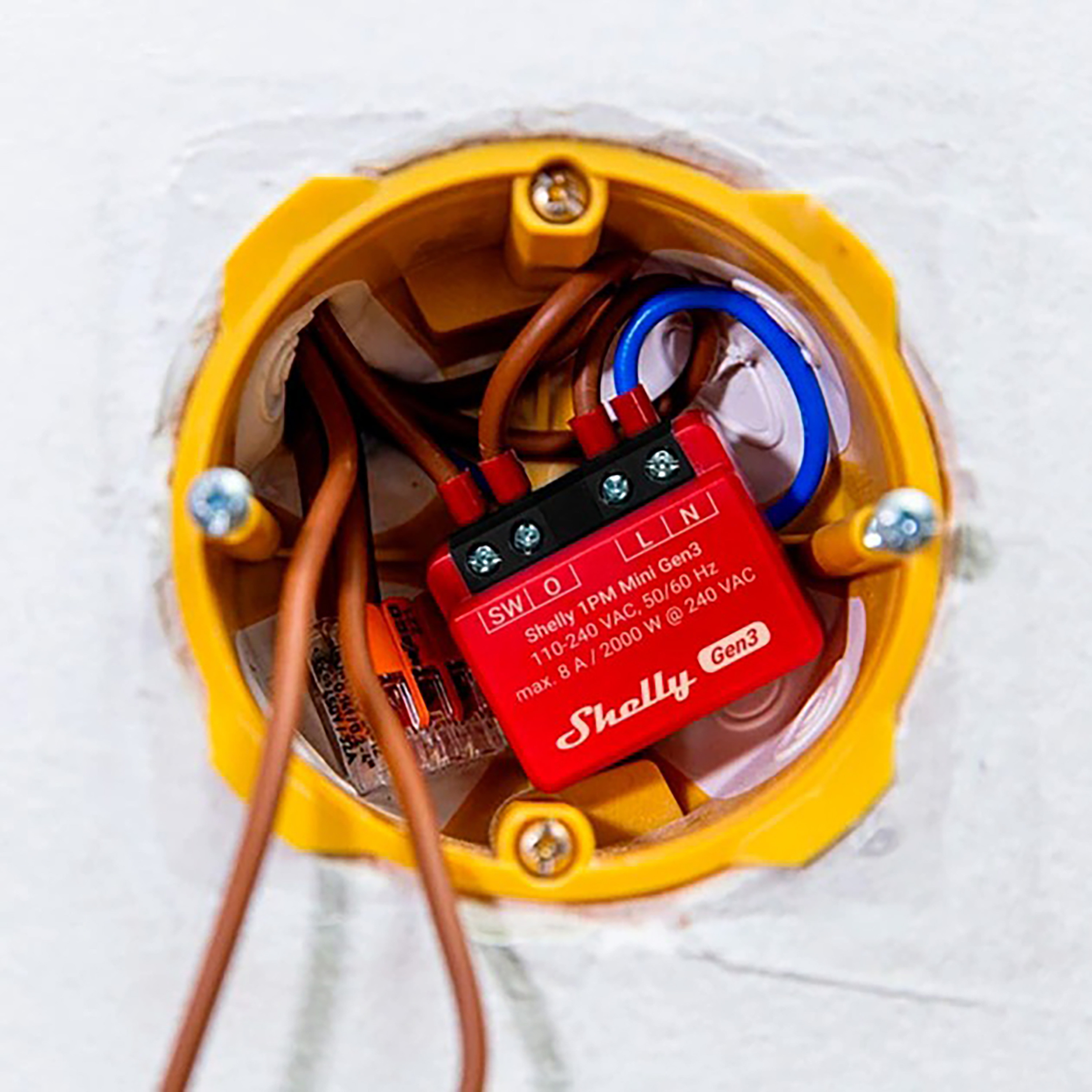 Czerwony Shelly 1PM Mini Gen3 znajduje się w żółtej skrzynce elektrycznej. Przewody są do niego podłączone.