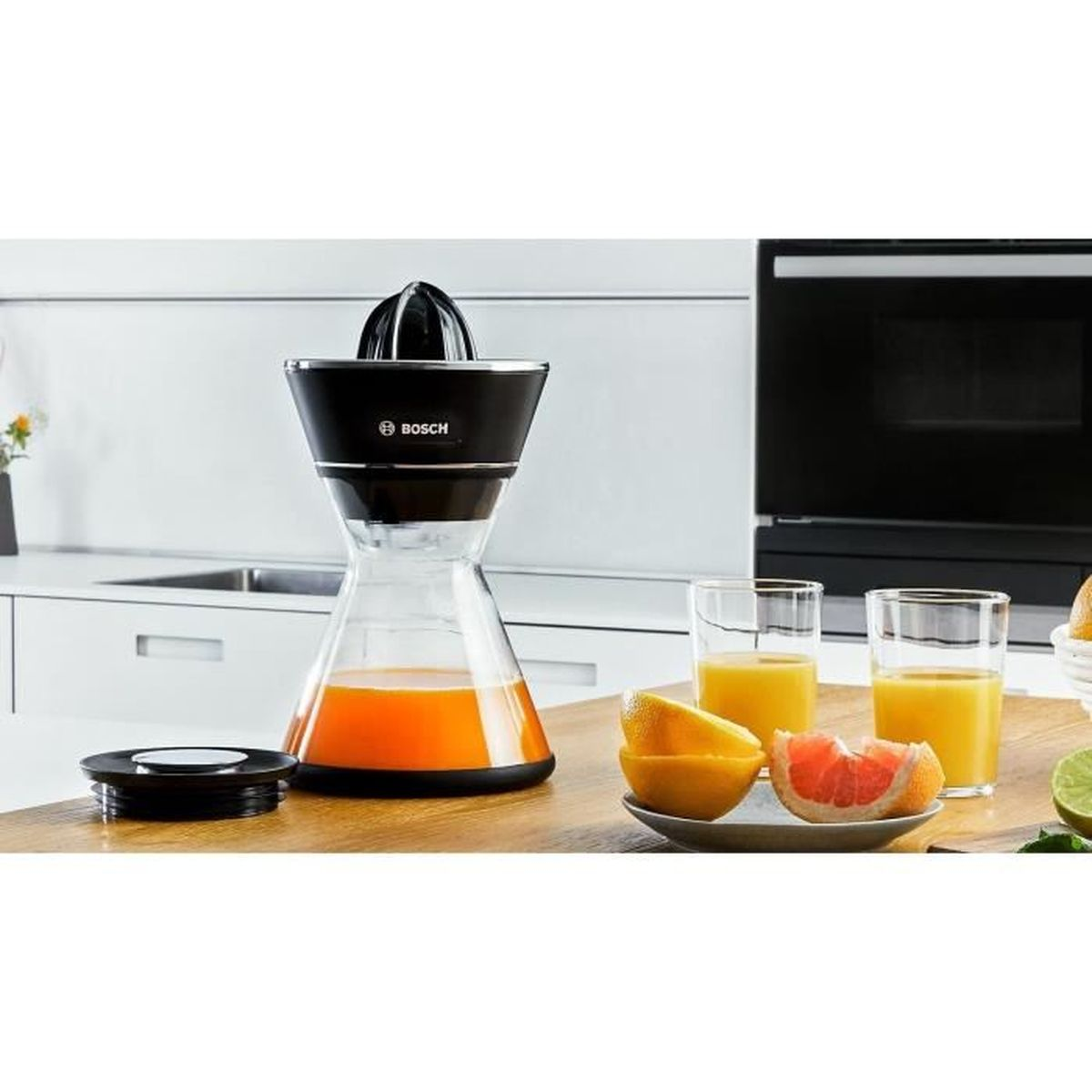Spremiagrumi con succo d'arancia e agrumi a fette su una superficie di legno, sfondo cucina.