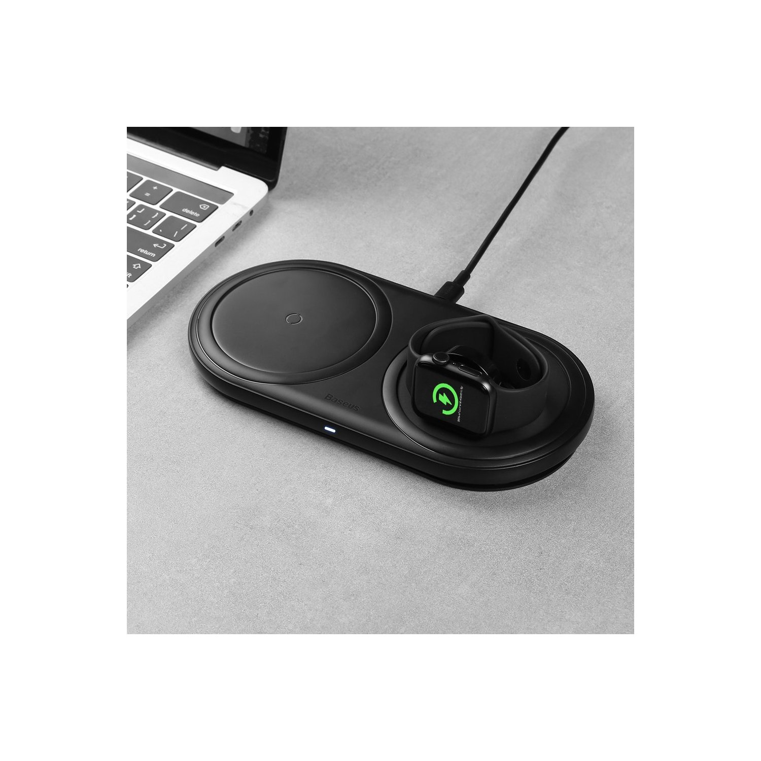 Eine schwarze, kabellose Ladestation mit einem Laptop und einer Apple Watch auf grauer Oberfläche.