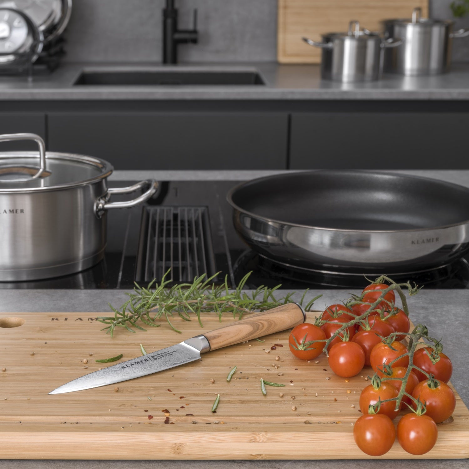 Küchenszene mit Schneidebrett, Messer und Tomaten. Edelstahl Töpfe im Hintergrund.