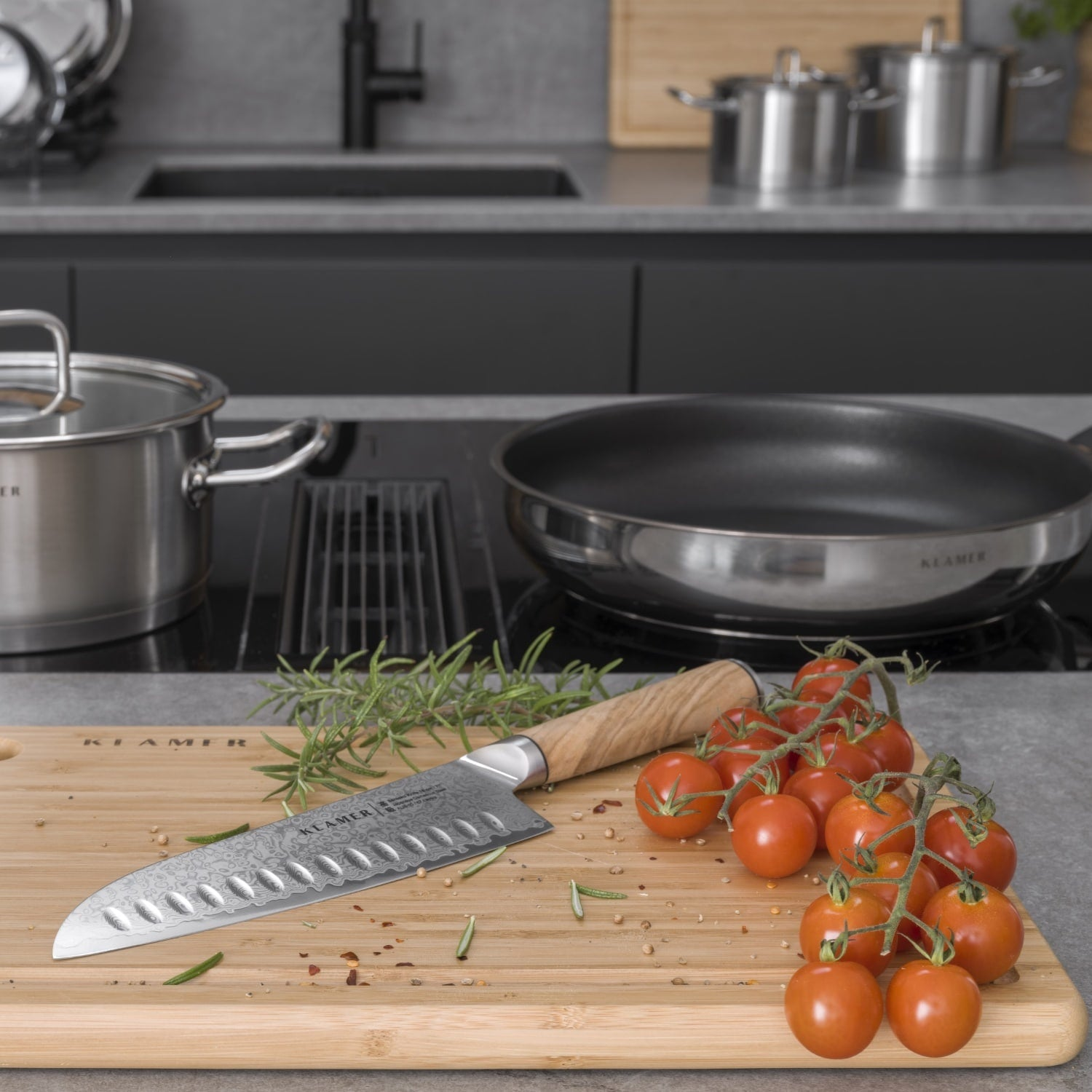Küchenszene mit Schneidebrett, Messer, Tomaten und Kochutensilien.