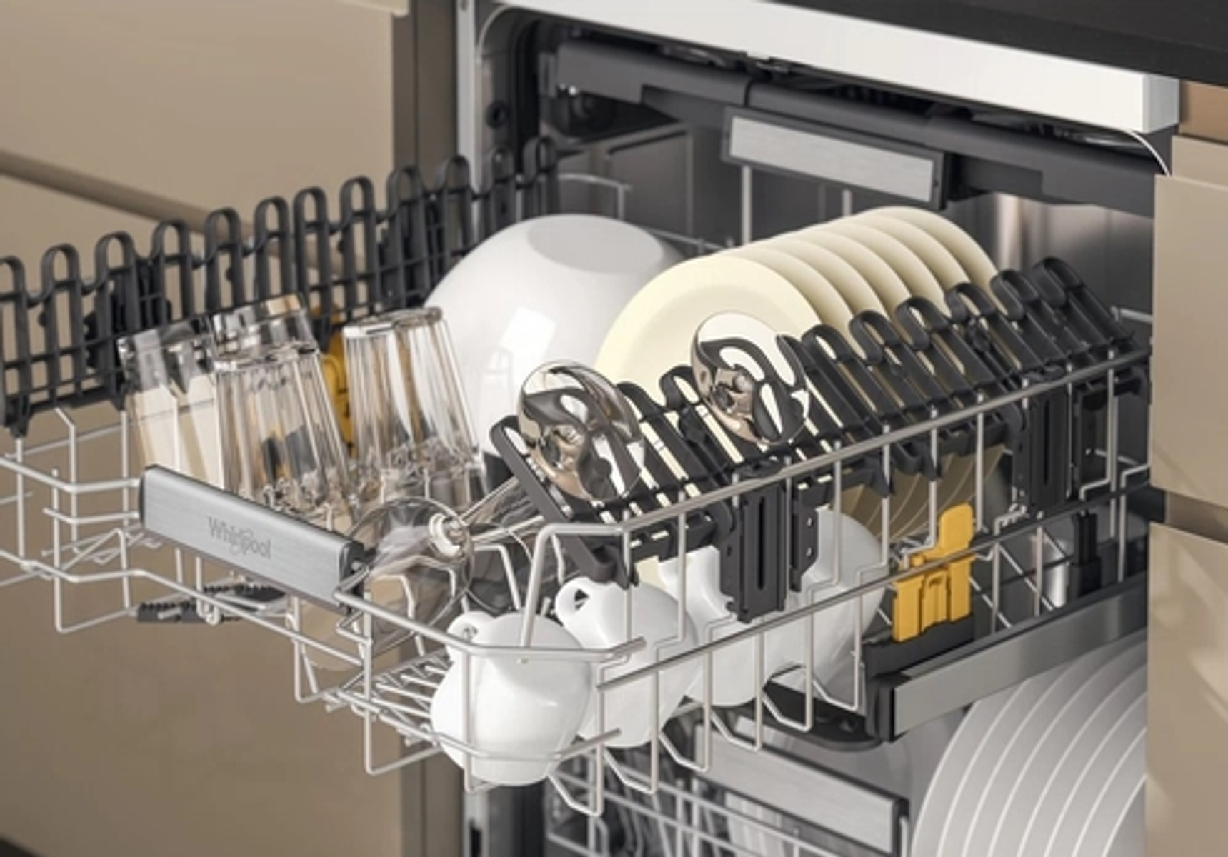 Wnętrze zmywarki ze szklankami, talerzami i filiżankami. Obecne są srebrne stojaki.