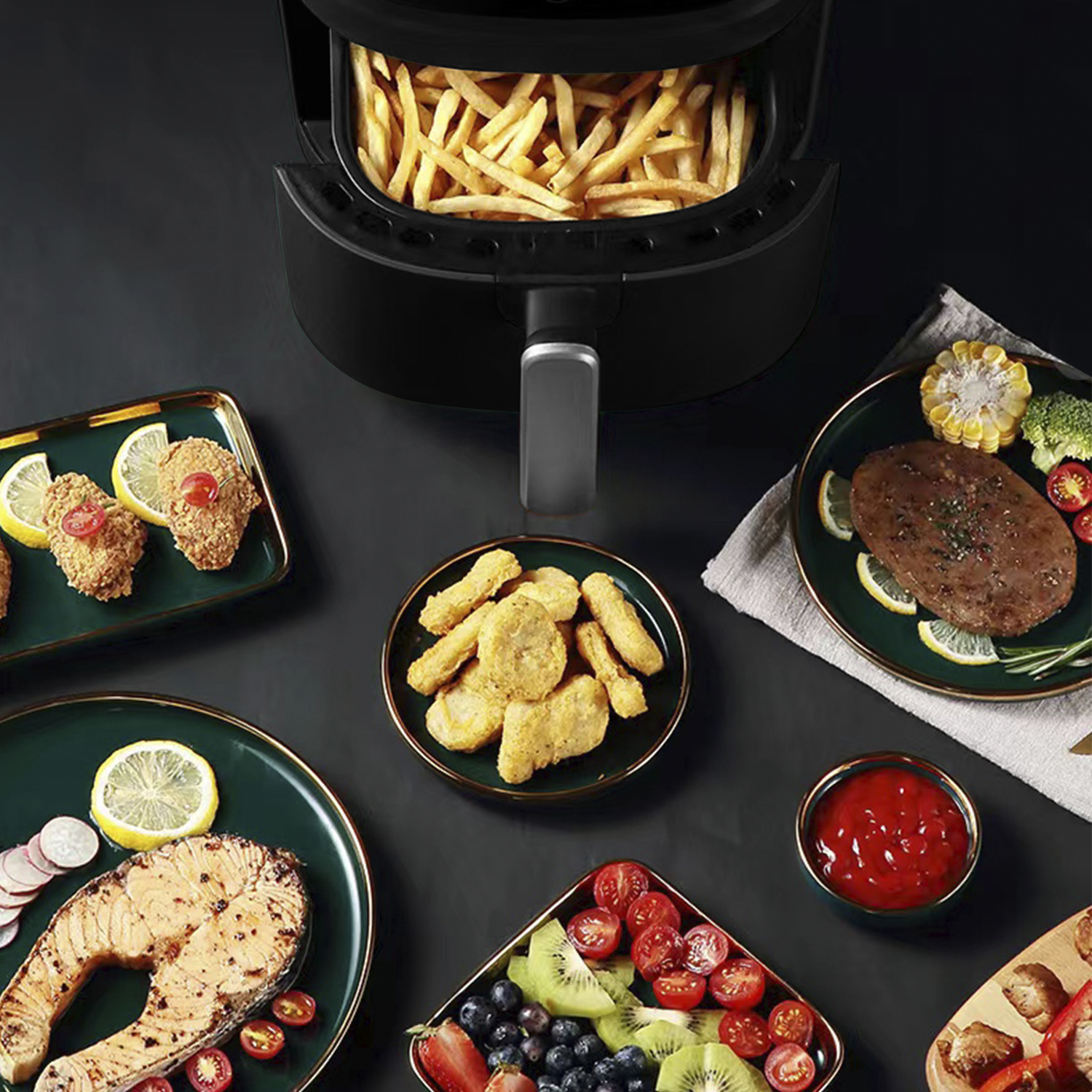 Una friggitrice ad aria nera con patatine fritte all'interno, circondata da piatti di cibo come pollo e bistecca.