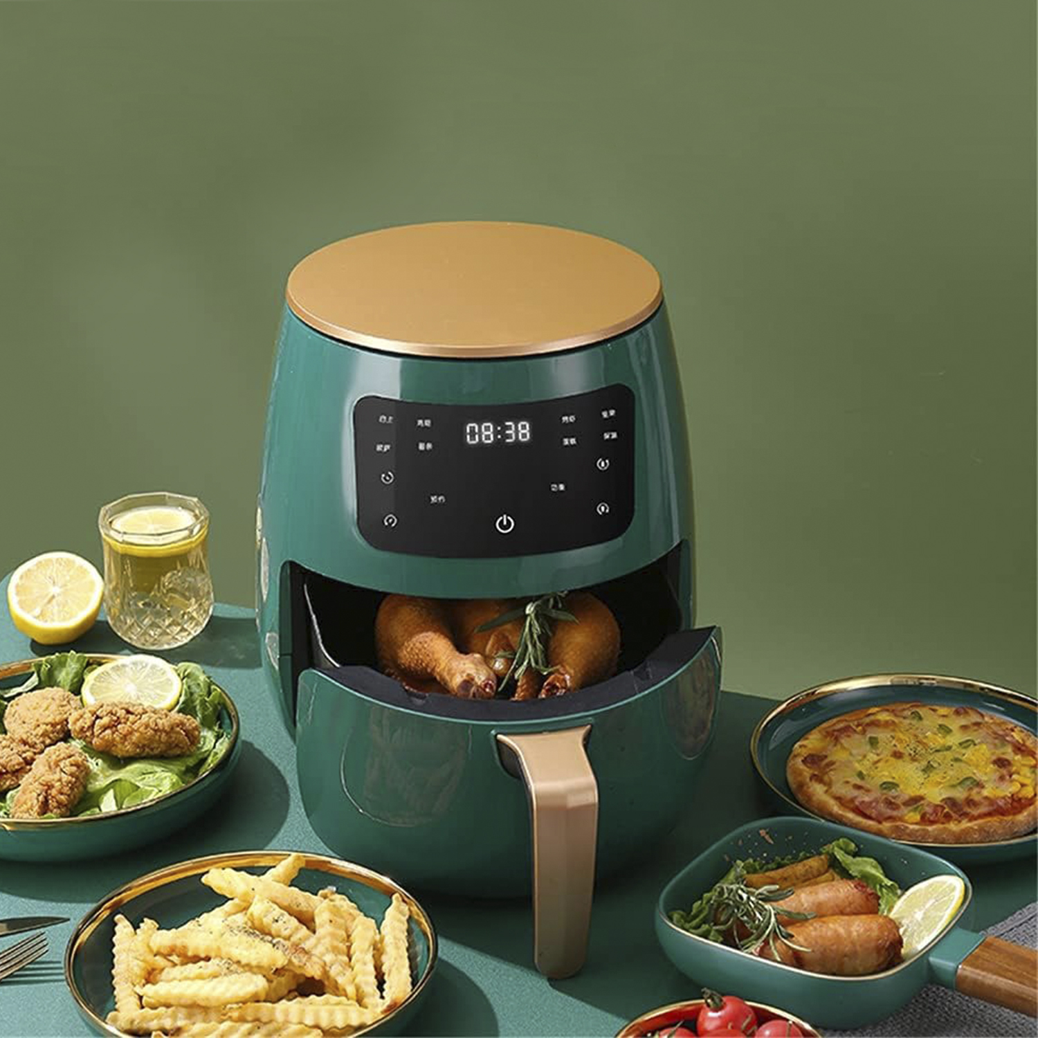 Eine Heißluftfritteuse mit Essen drumherum, darunter Hähnchen, Pommes und Pizza. Es steht auf einer grünen Oberfläche.