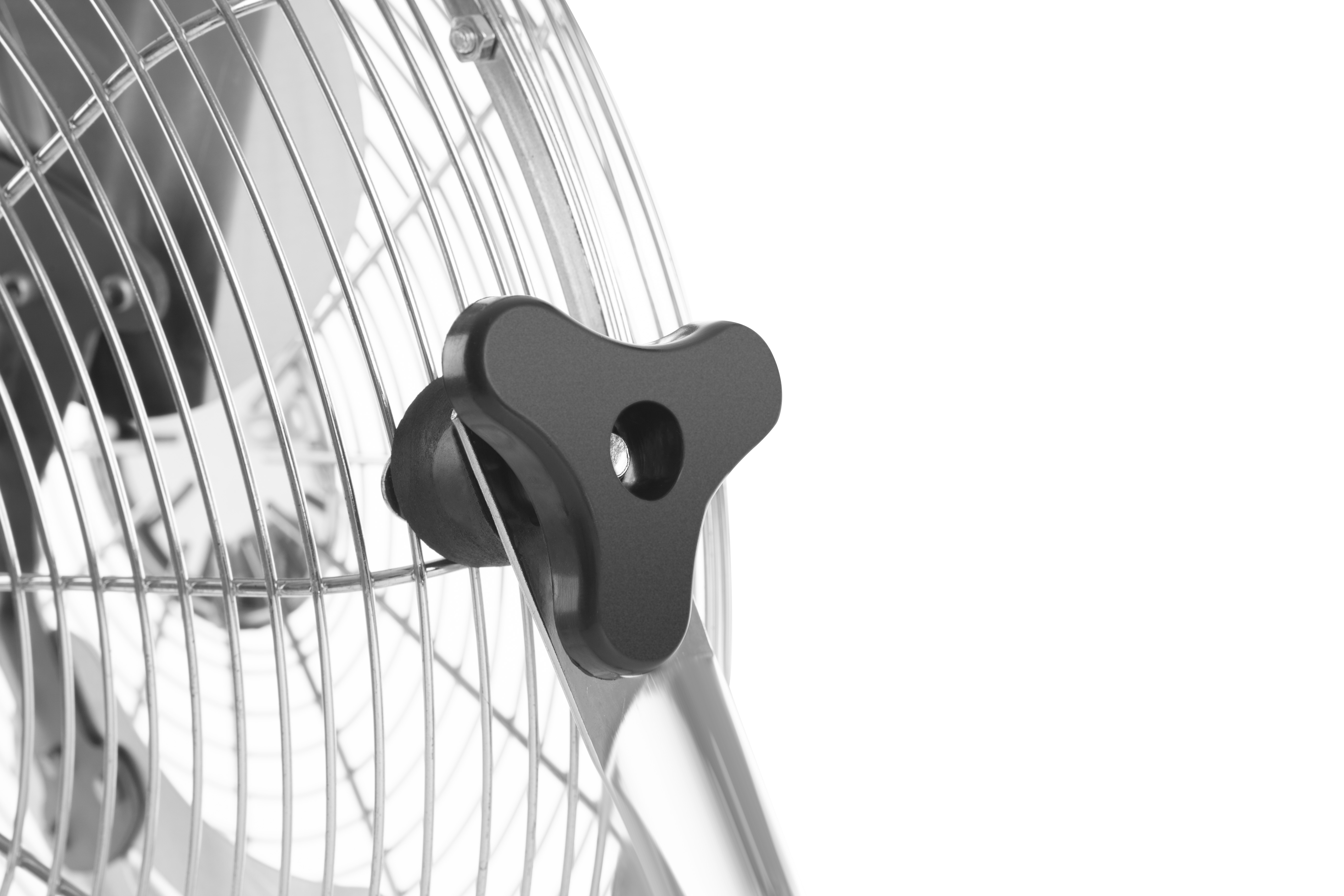 Primo piano di una manopola nera su un ventilatore. Sono visibili le pale e la rete del ventilatore. Lo sfondo è bianco.