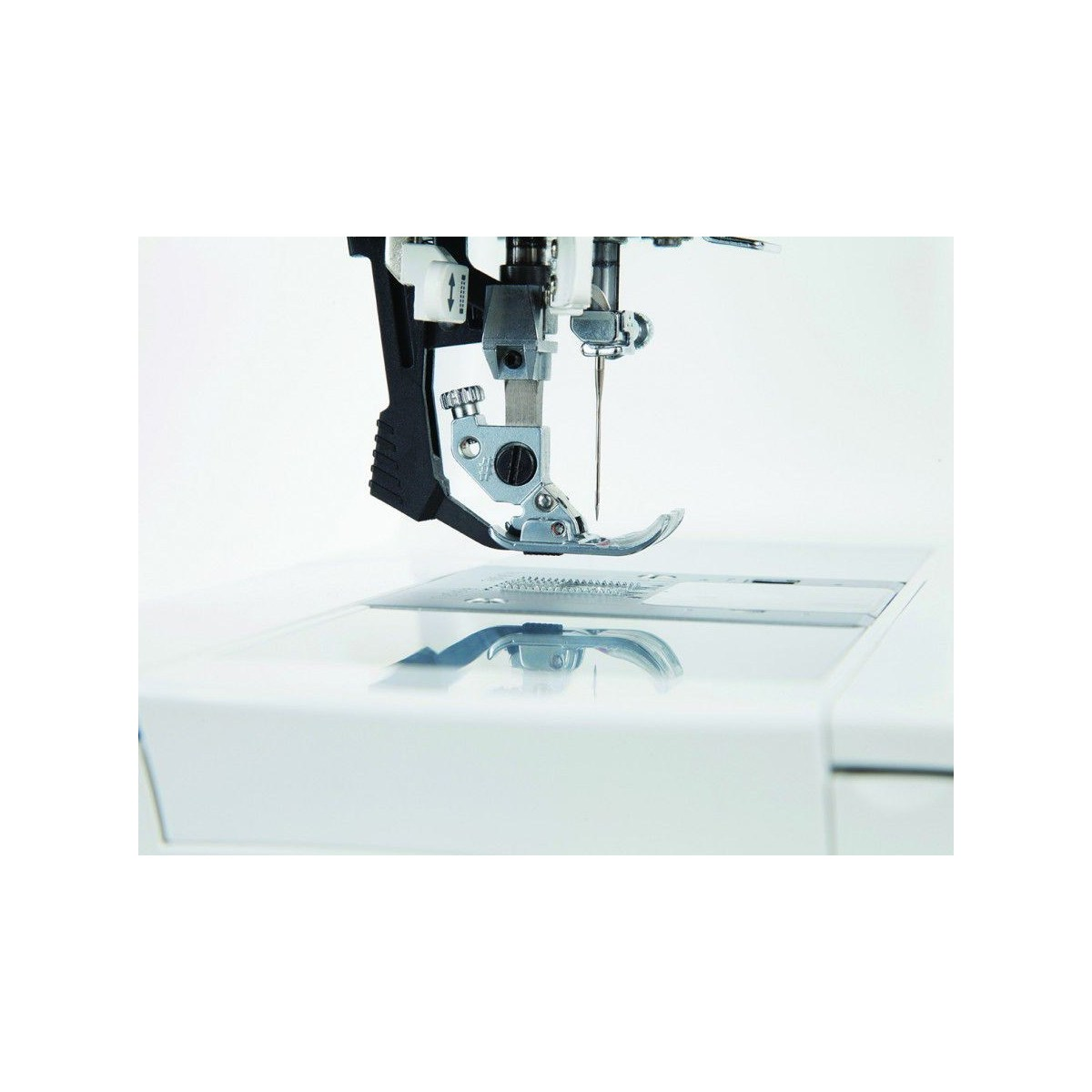 Zbliżenie stopki maszyny do szycia, igły i płytki. Igła jest w pozycji dolnej.