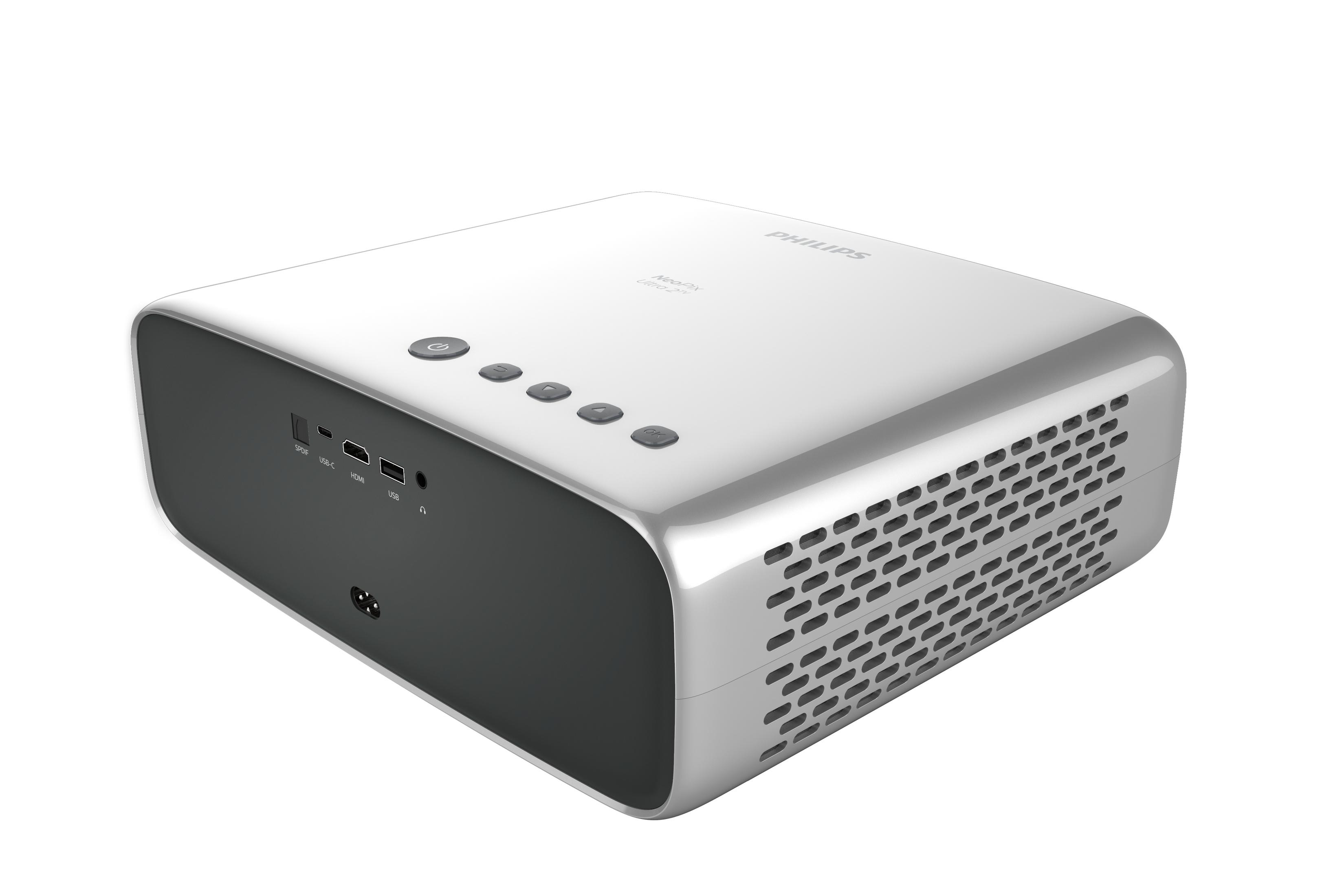 Biało-srebrny projektor z widocznymi przyciskami i portami. Widok pod kątem, białe tło. Logo 'PHILIPS'.
