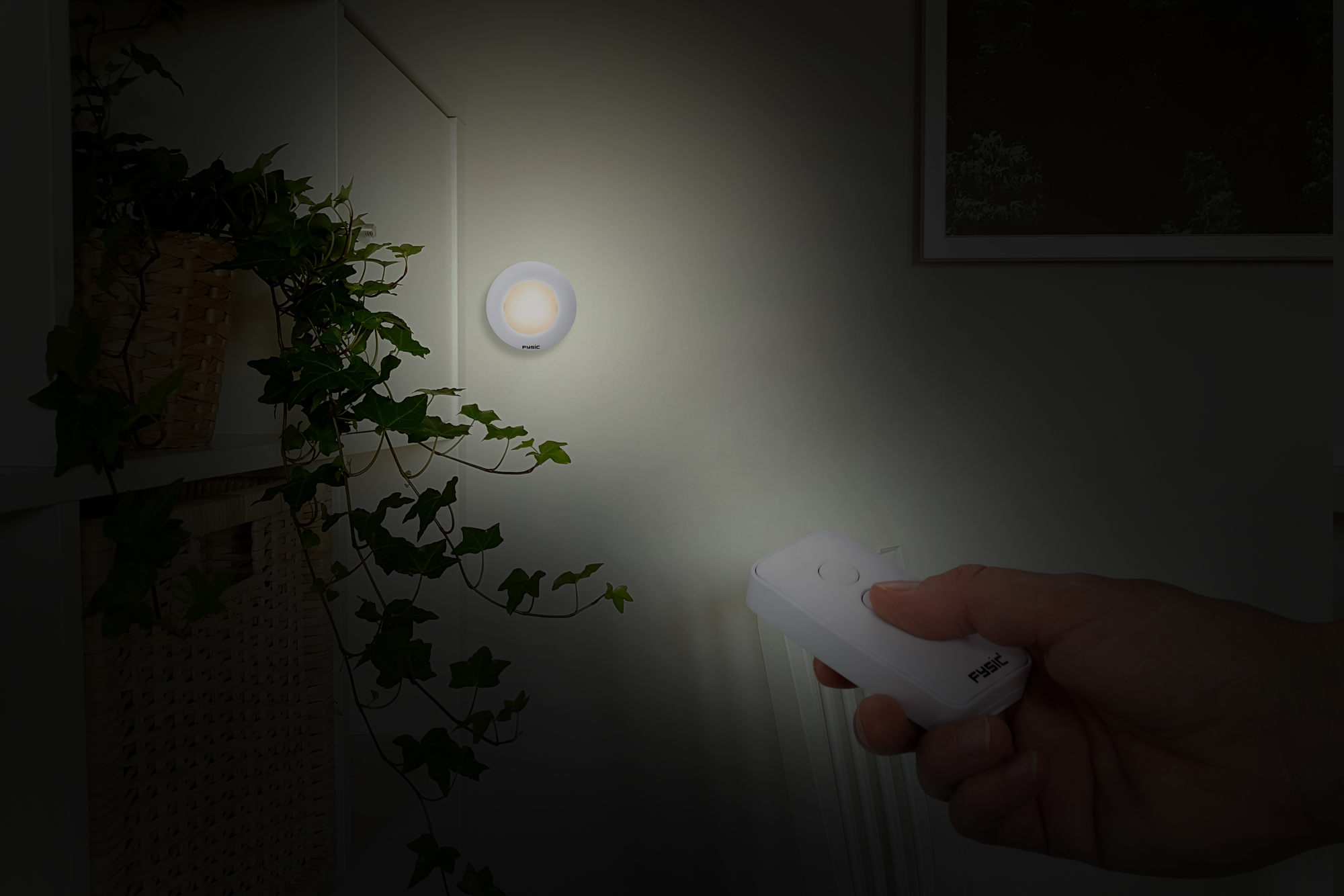 A wall with a small, round, white light. A hand holding a remote in the dark.