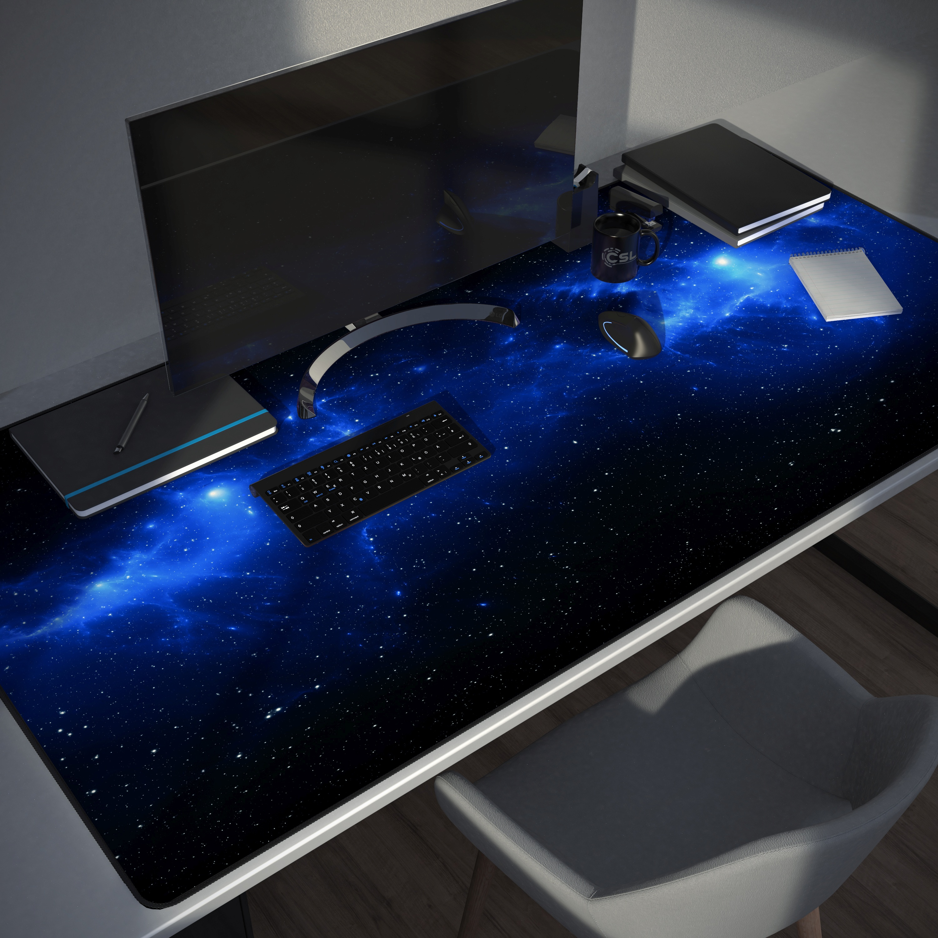 Schreibtisch mit Mauspad mit Galaxy-Design, Tastatur, Monitor und anderen Büroartikeln.