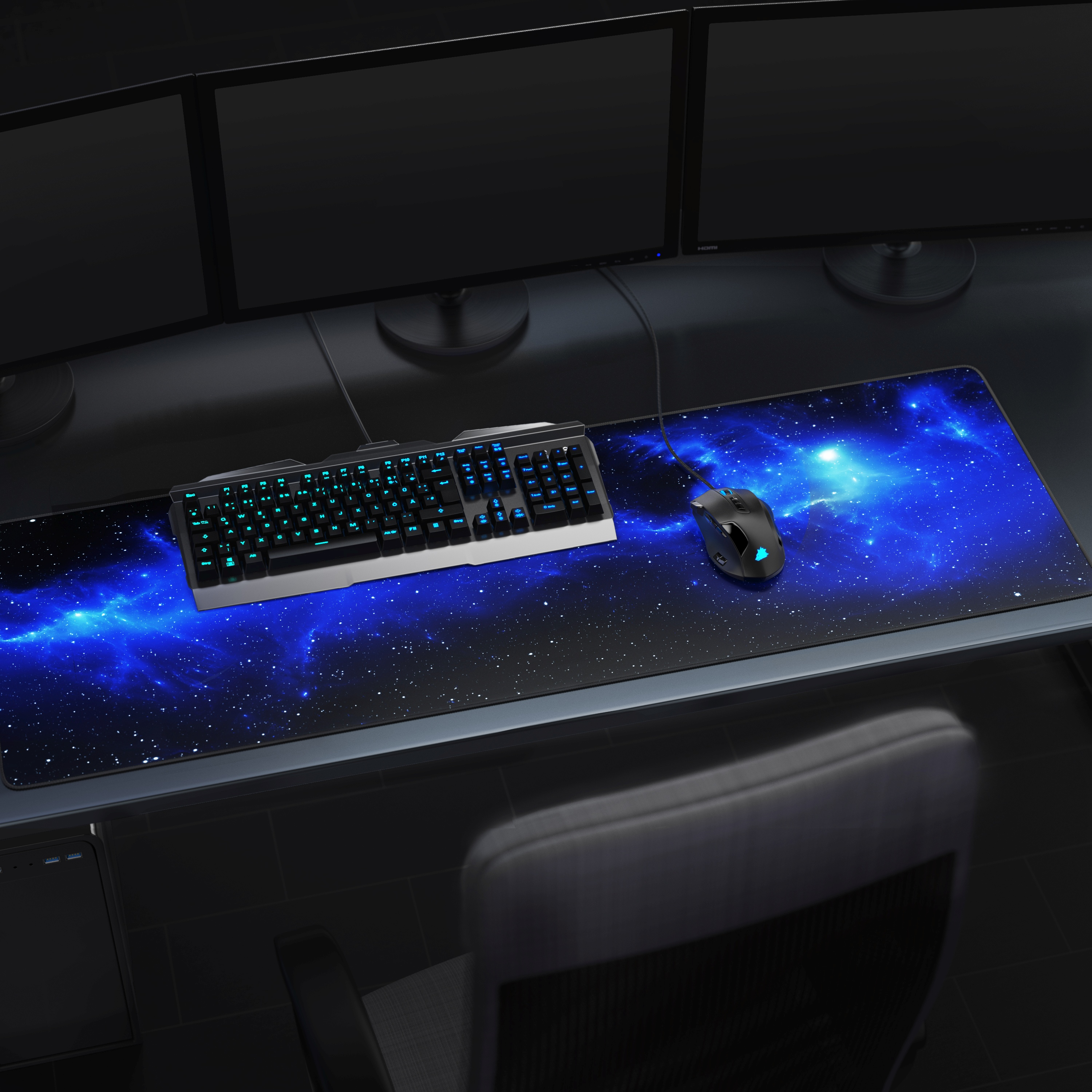 Schreibtisch mit Tastatur, Maus und drei Monitoren. Mauspad zeigt eine blaue Galaxie.