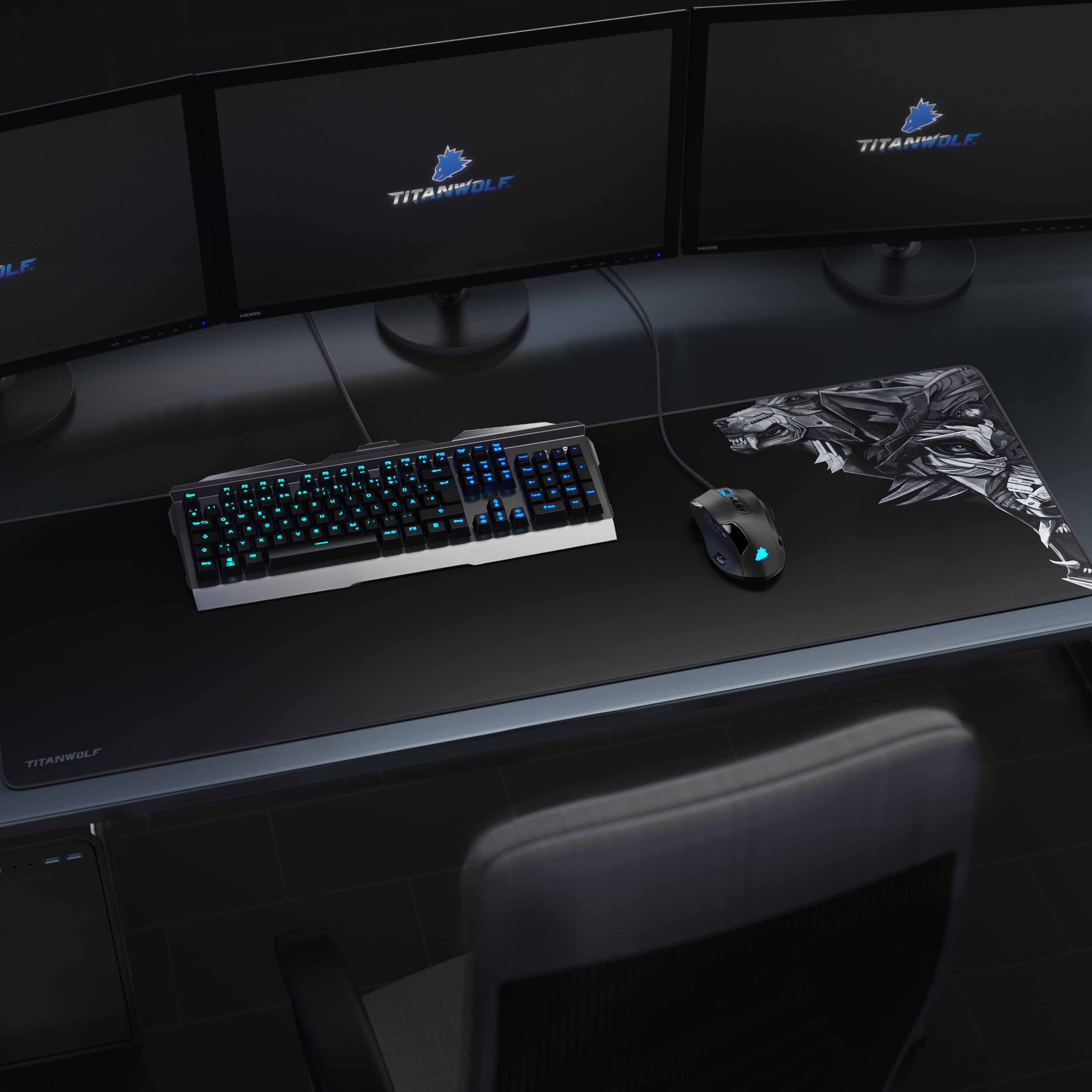 Gaming-Setup mit Tastatur, Maus und drei Monitoren auf einem schwarzen Mauspad.