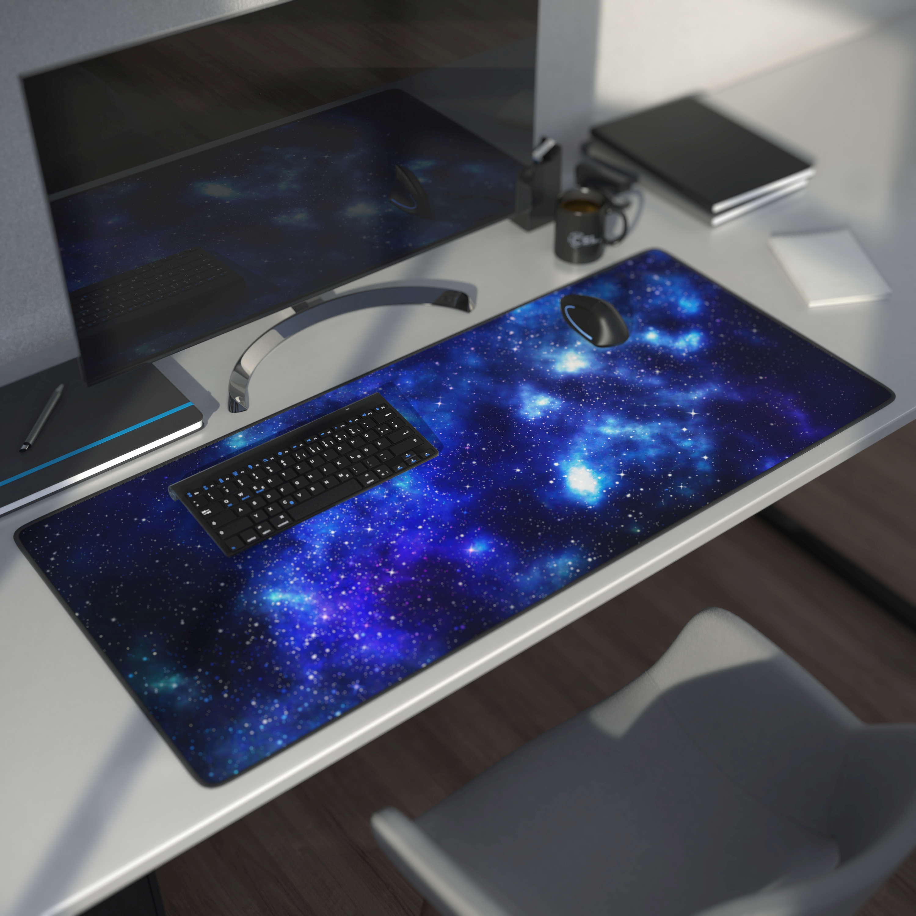 Ein Gaming-Mauspad mit Galaxie-Design, Tastatur und Computer auf einem Schreibtisch.