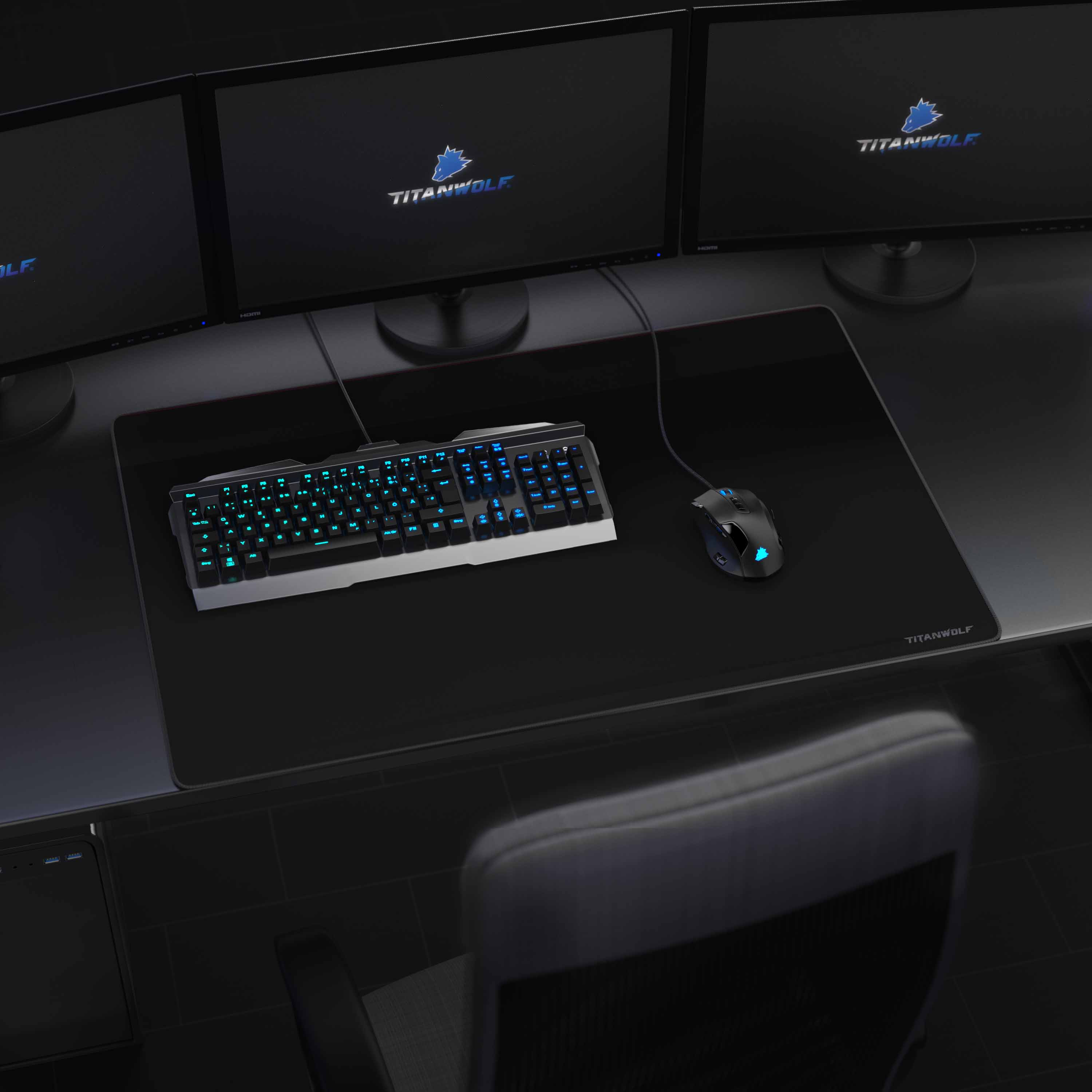 Gaming-Setup mit drei Monitoren, Tastatur und Maus auf einem schwarzen Schreibtisch. Neutraler Hintergrund.