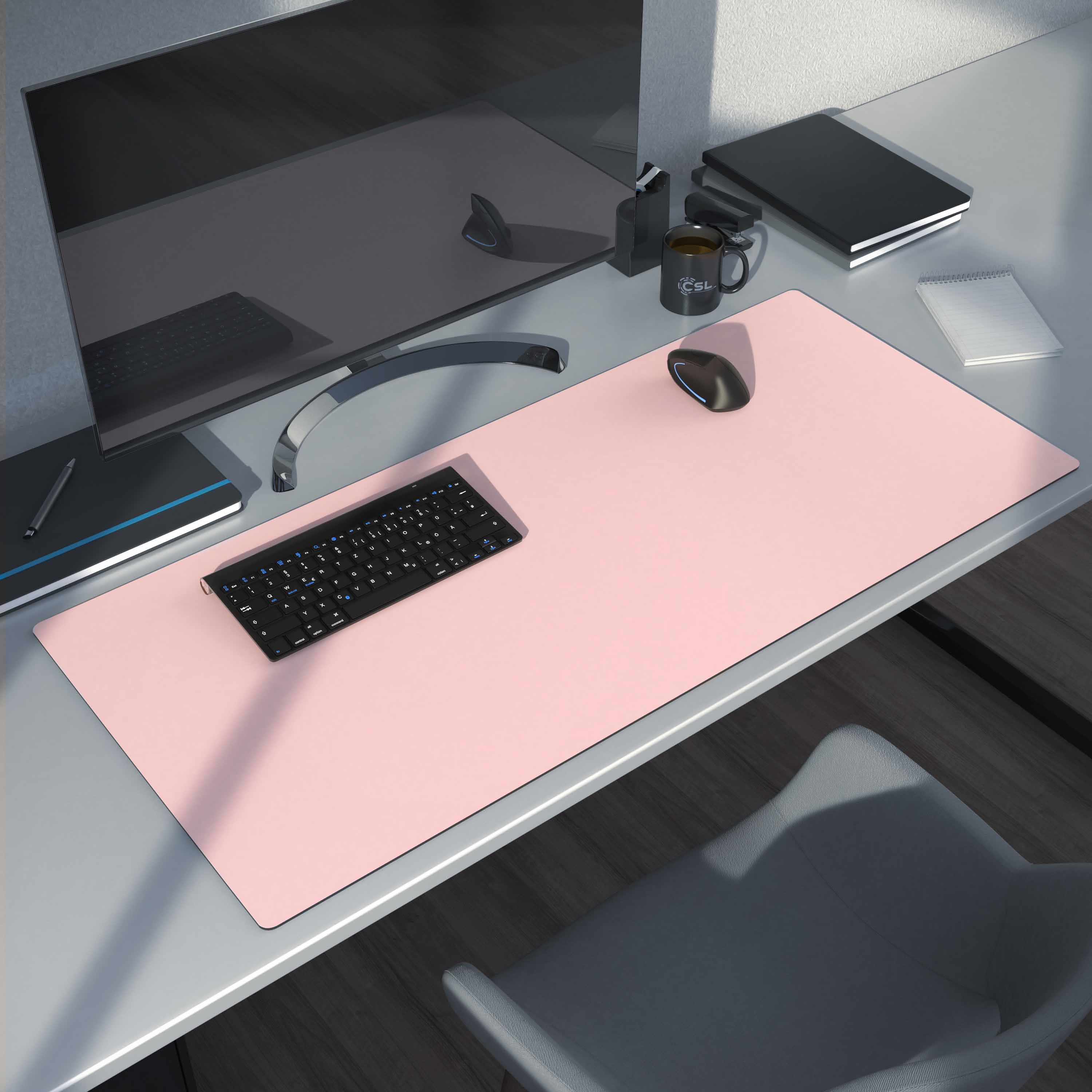 Schreibtisch mit rosa Matte, Tastatur, Maus, Monitor und Zubehör.