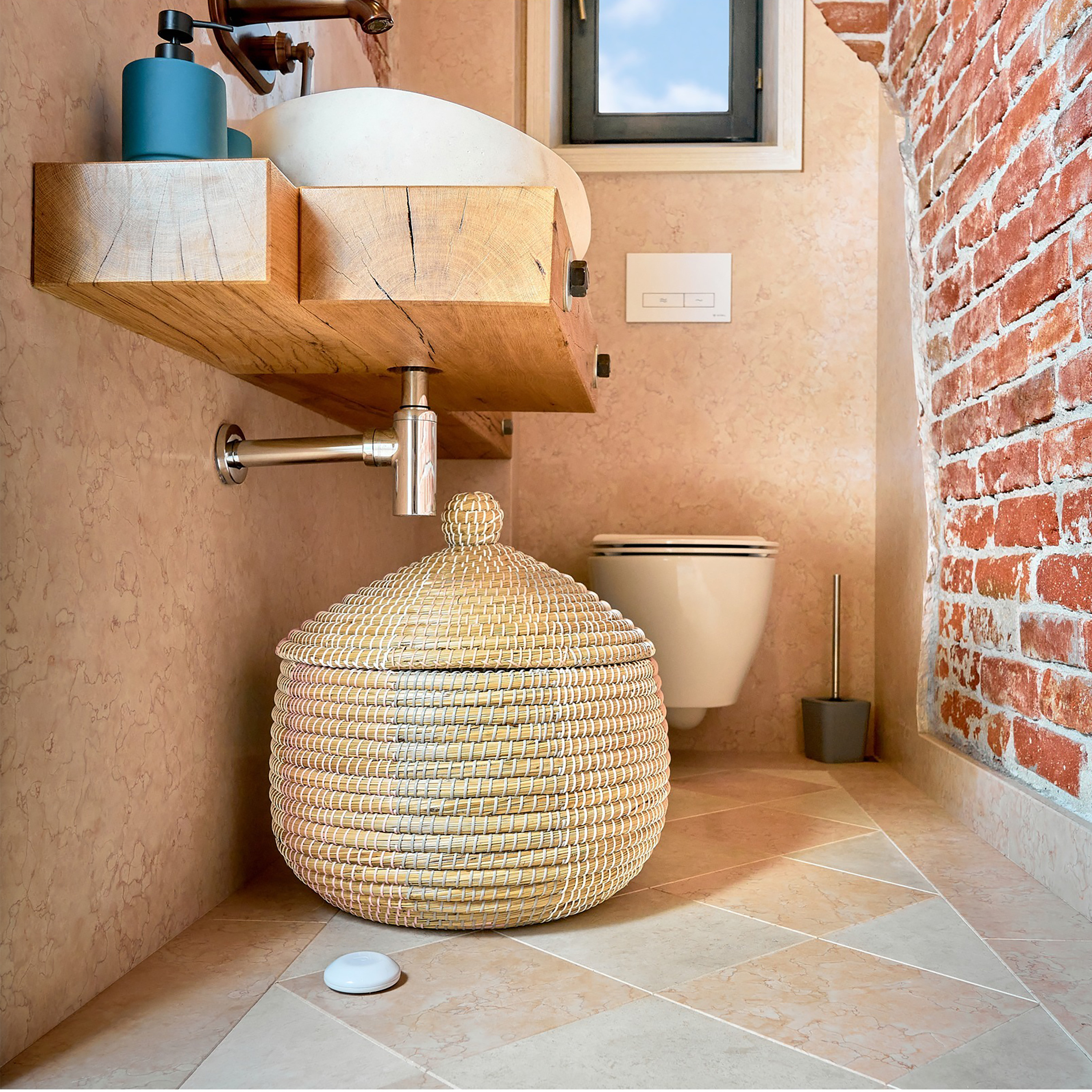 Wnętrze łazienki z drewnianą umywalką i wiklinowym koszem.