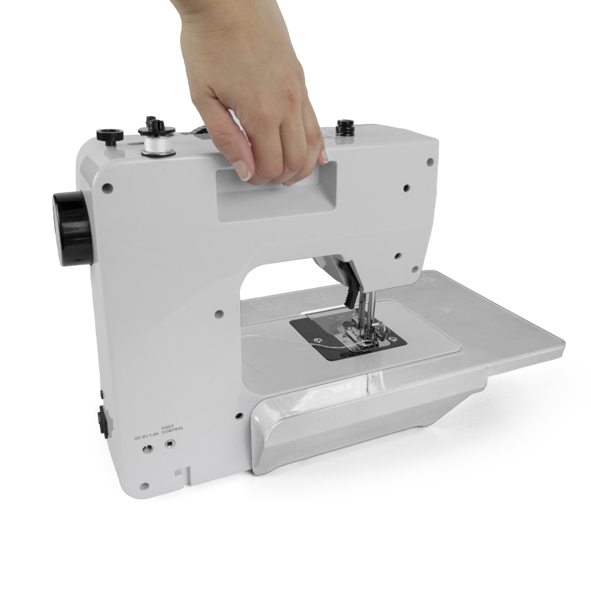 Ręka trzymająca białą maszynę do szycia.