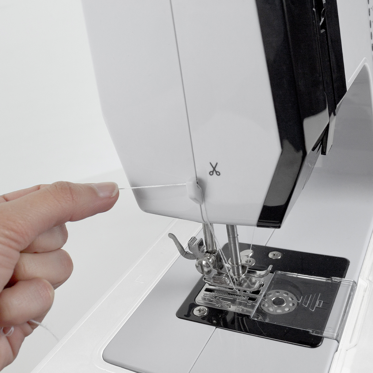 Maszyna do szycia z ręką trzymającą nić. Biała maszyna. Nić przechodzi przez maszynę.