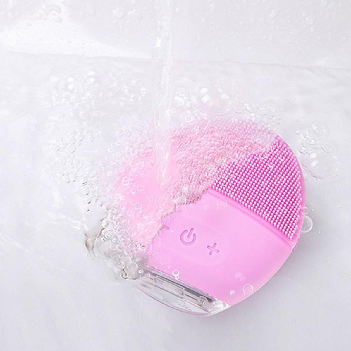 Cepillo de limpieza facial rosa con agua fluyendo, fondo blanco.