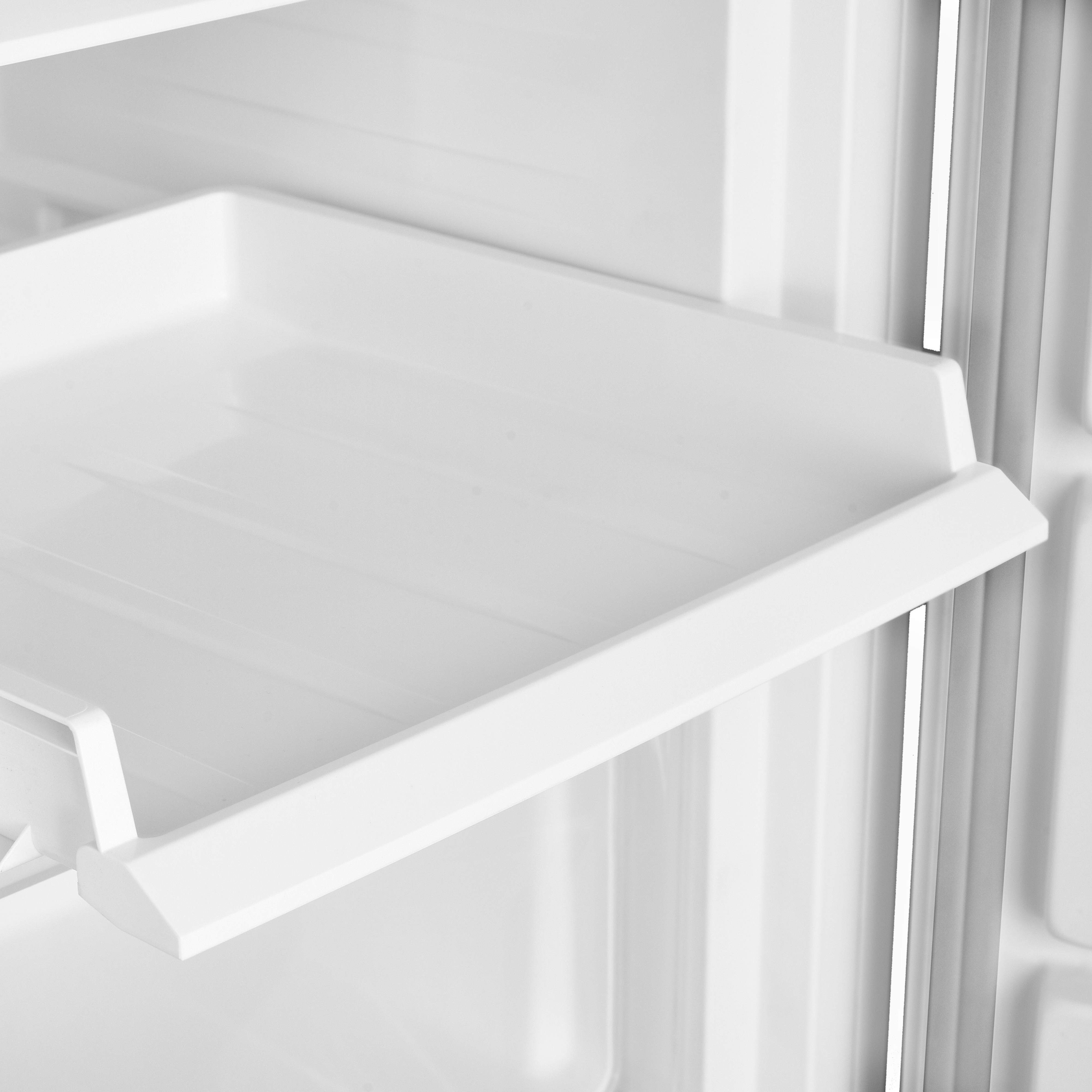 White refrigerator shelf. It's empty, made of plastic, and inside a refrigerator.