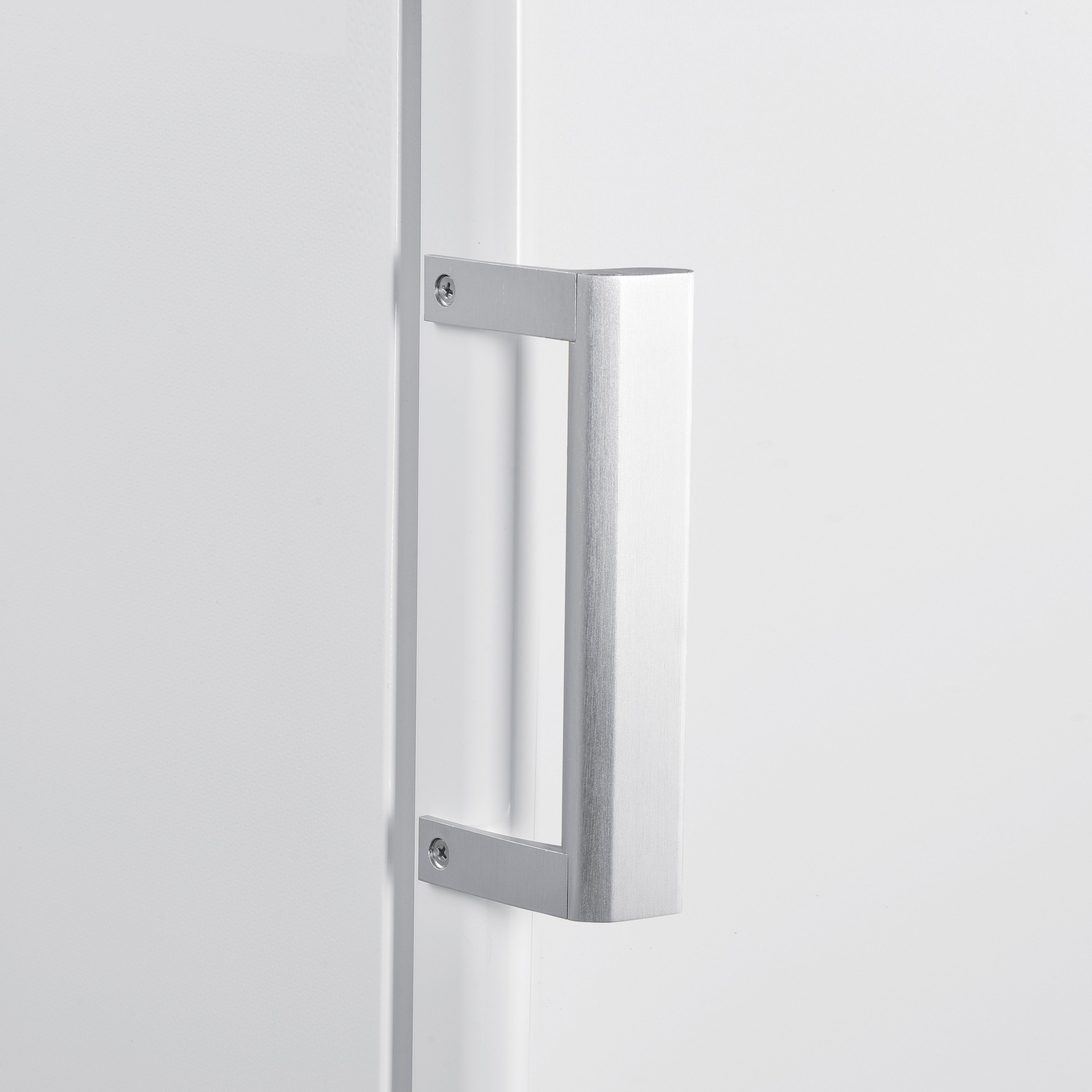 Silver door handle, rectangular shape, mounted on a white door with screws.