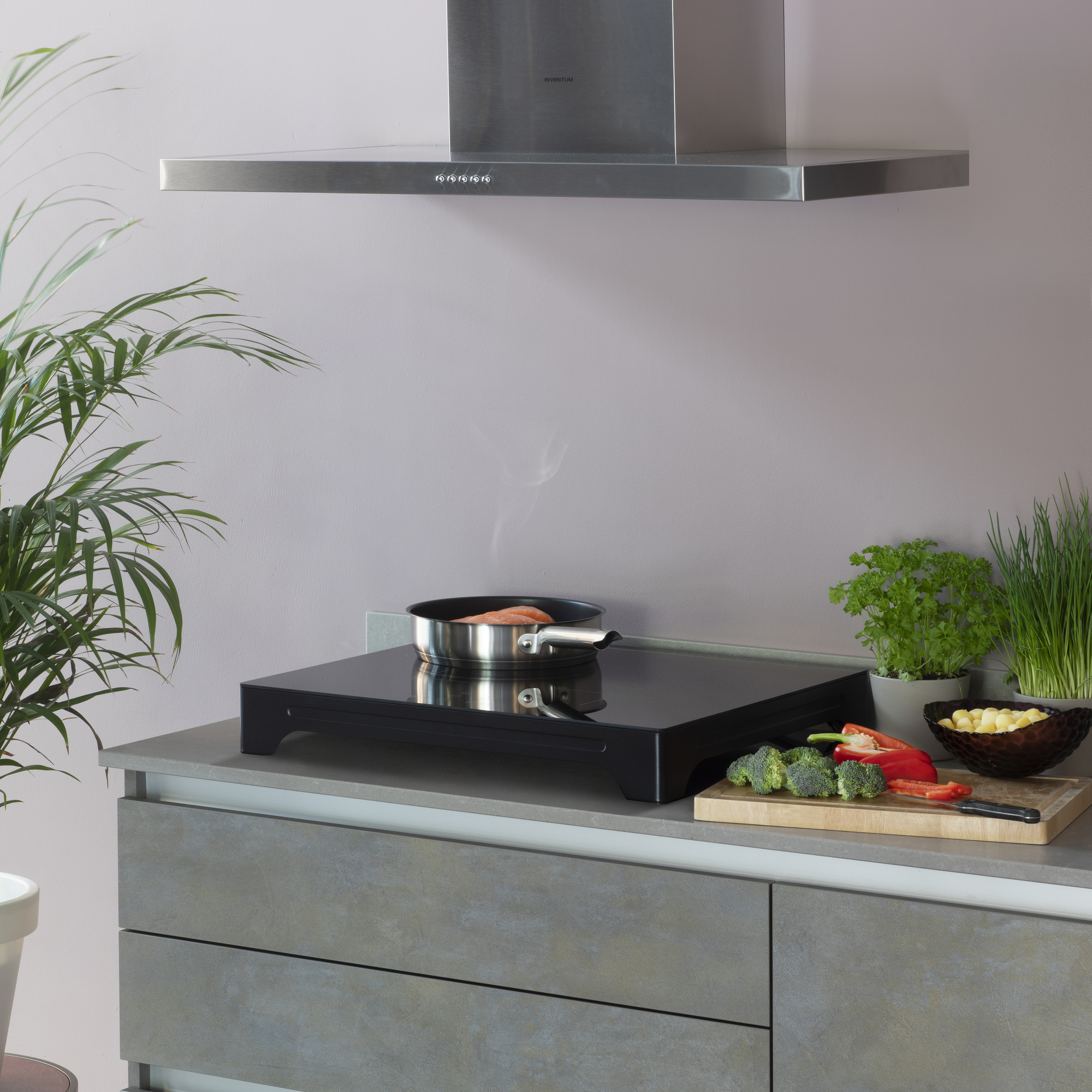 Keuken met een kookplaat, pan met eten en verse ingrediënten op een aanrecht.