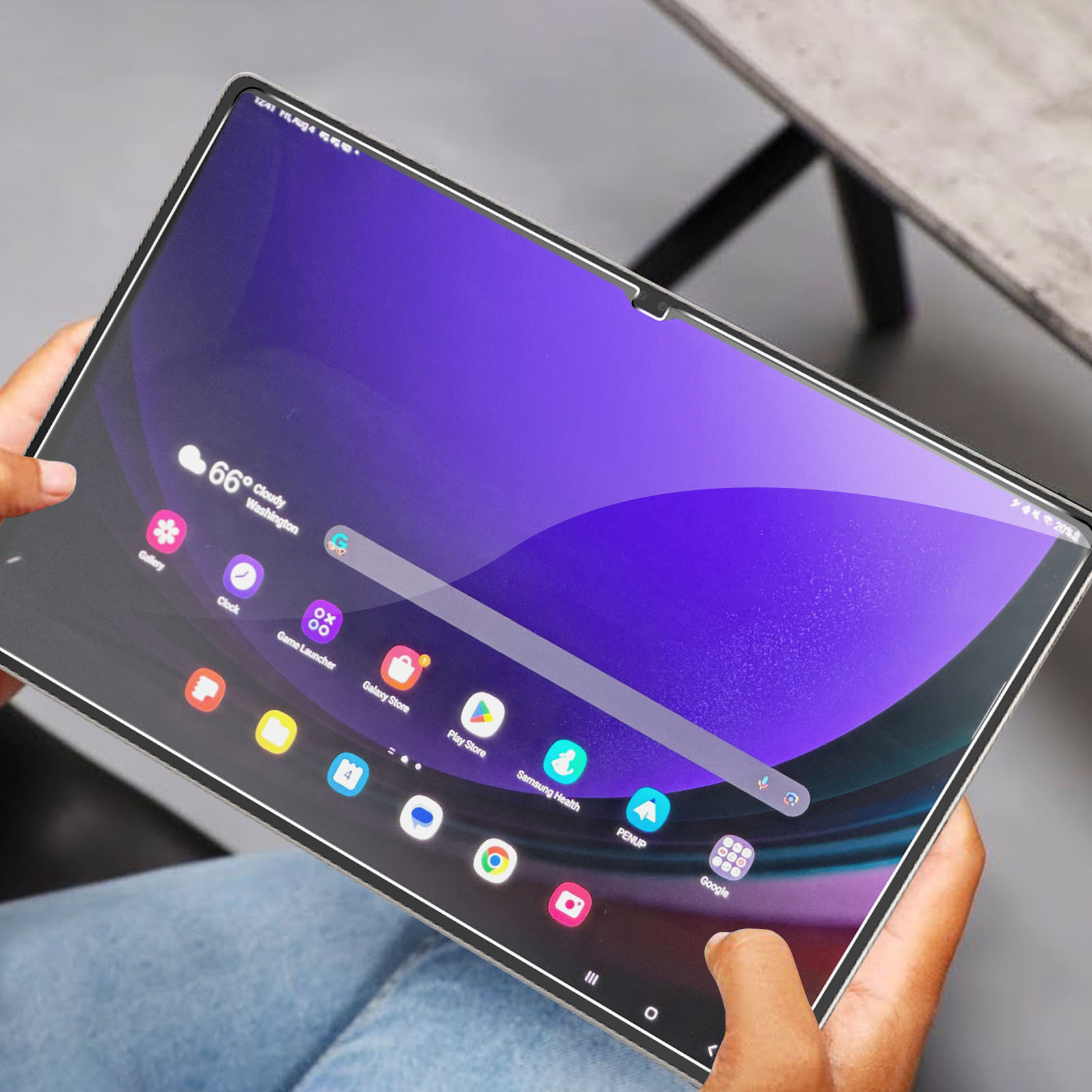 Une tablette montrant une interface violette, tenue par des mains, avec un protecteur d'écran.
