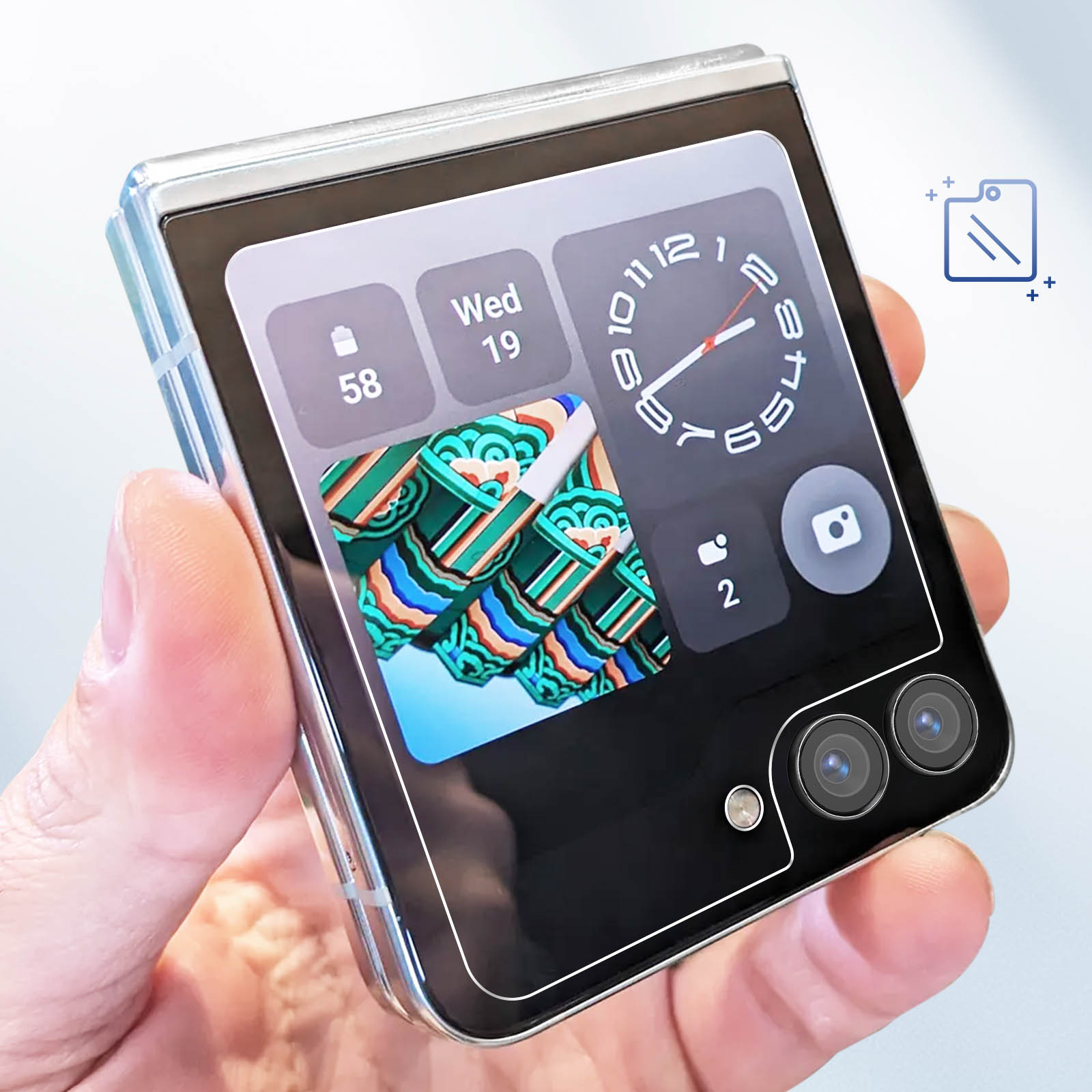 Foldable phone in hand. Screen shows time, date, and a picture. The phone is silver and black.