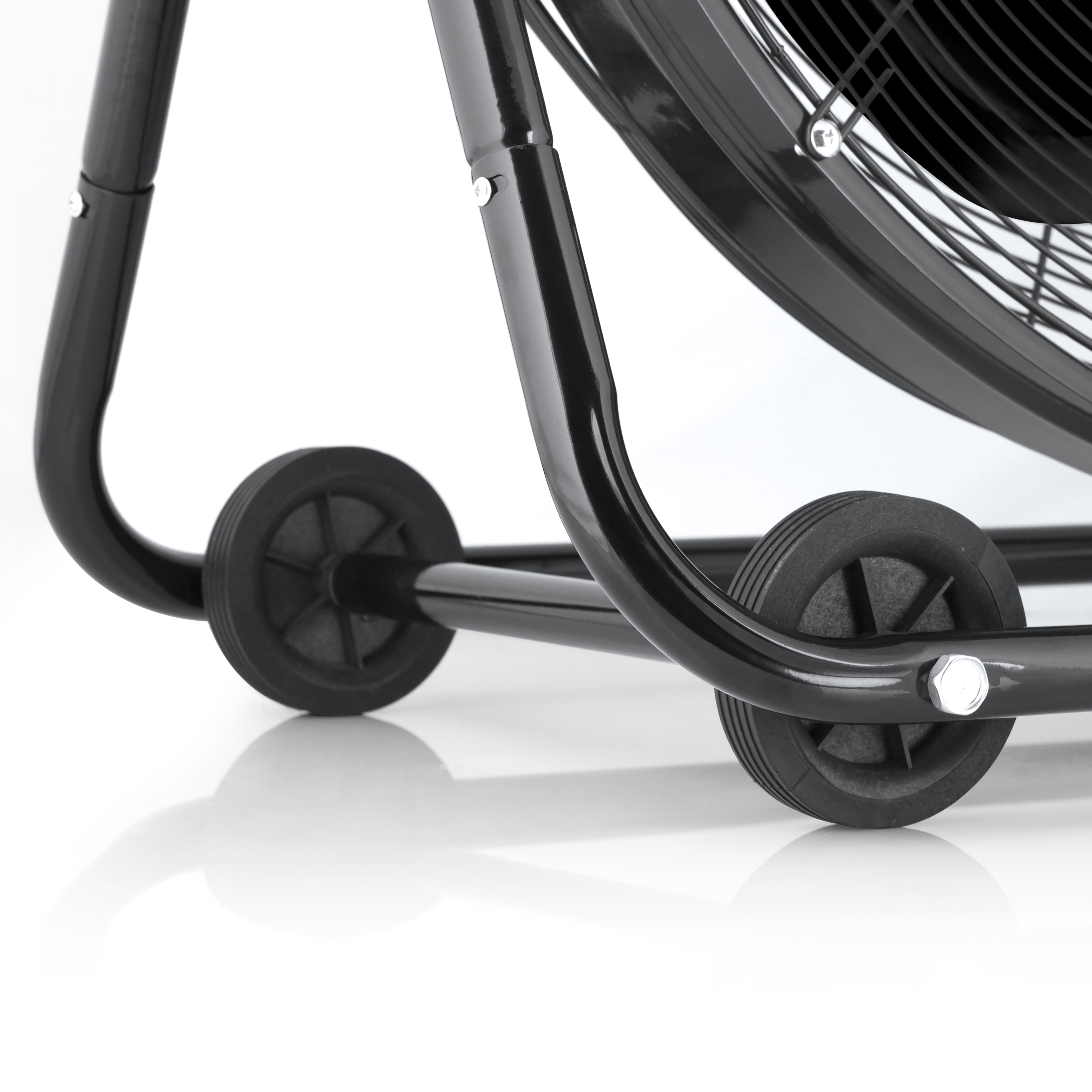 Parte inferior de un ventilador negro con ruedas sobre superficie blanca.
