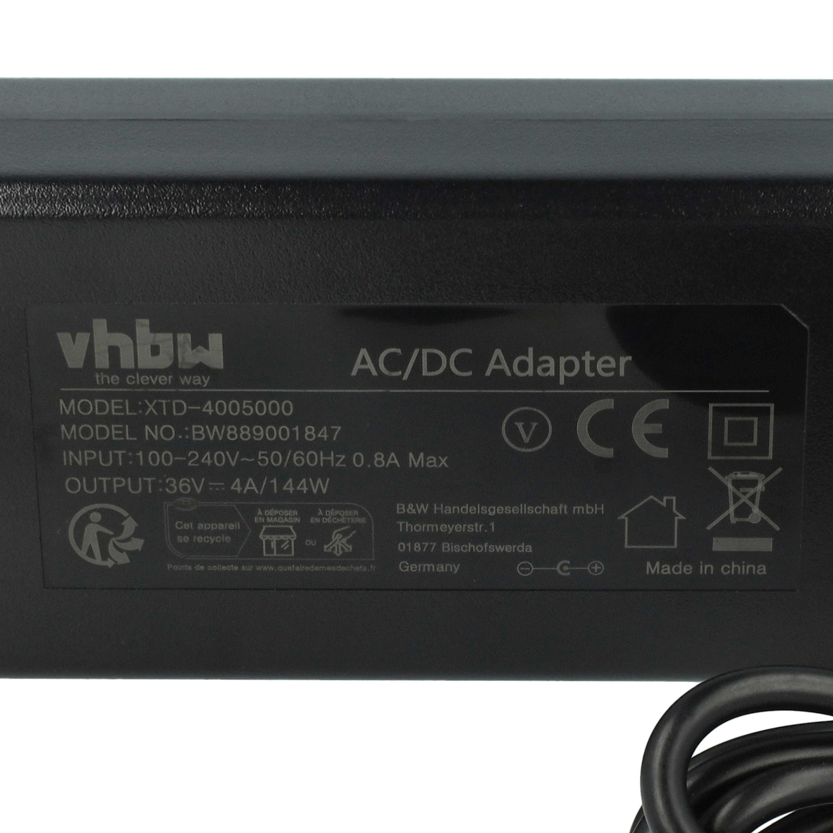 Nahaufnahme eines schwarzen AC/DC-Adapters mit weißem Text darauf. Schwarzes Kabel ist angeschlossen.