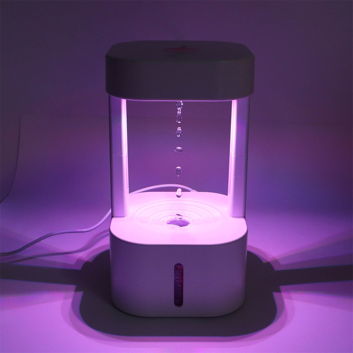 Weißer Luftbefeuchter mit fallenden Wassertröpfchen, beleuchtet von violettem Licht.