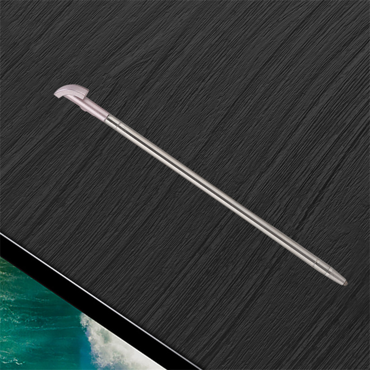 Silberner Stylus-Stift auf strukturierter schwarzer Oberfläche. Stift ist angewinkelt.