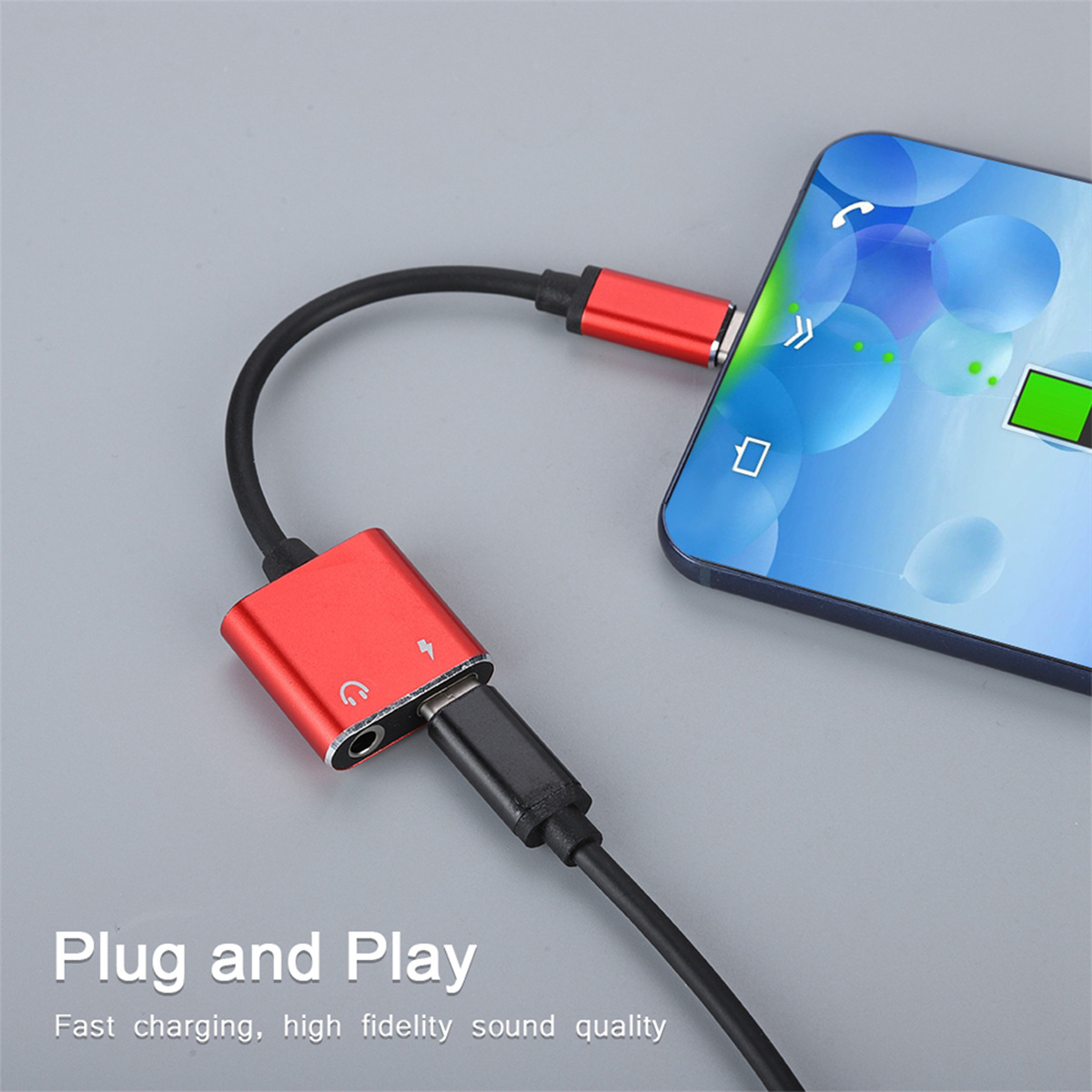 Roter Adapter mit zwei Anschlüssen und einem schwarzen Kabel, das mit einem Telefon und einem Ladegerät verbunden ist.