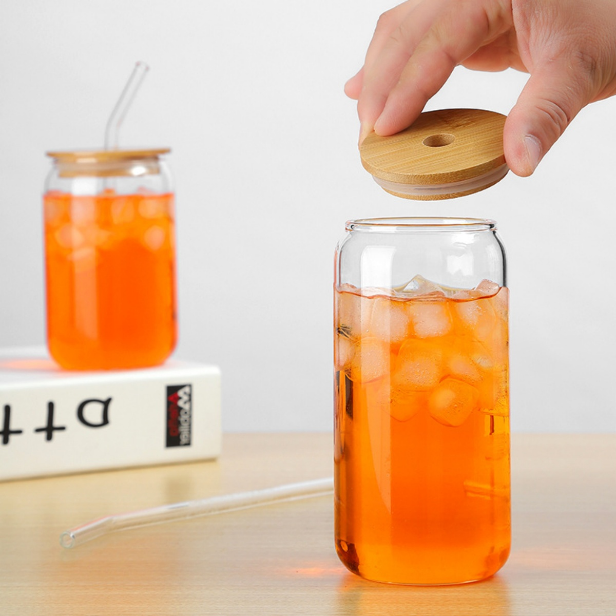 Zwei Gläser mit orangener Flüssigkeit. Eines mit Deckel und Strohhalm, das andere mit Eis und Strohhalm.