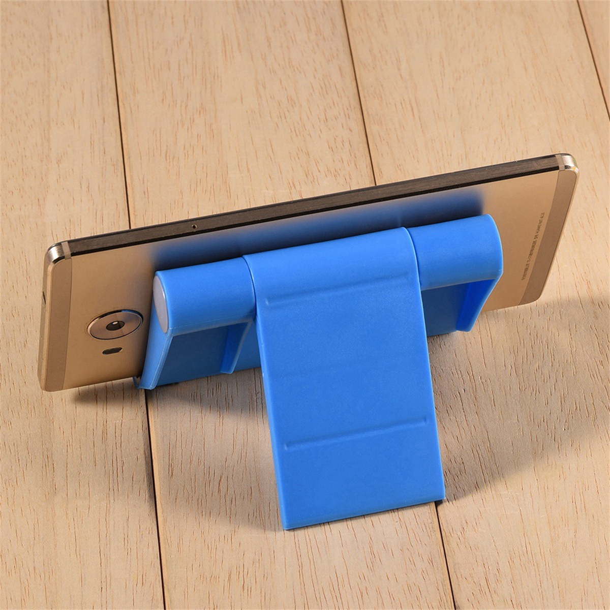 Ein blauer Telefonständer hält ein goldenes Telefon auf einem Holztisch.