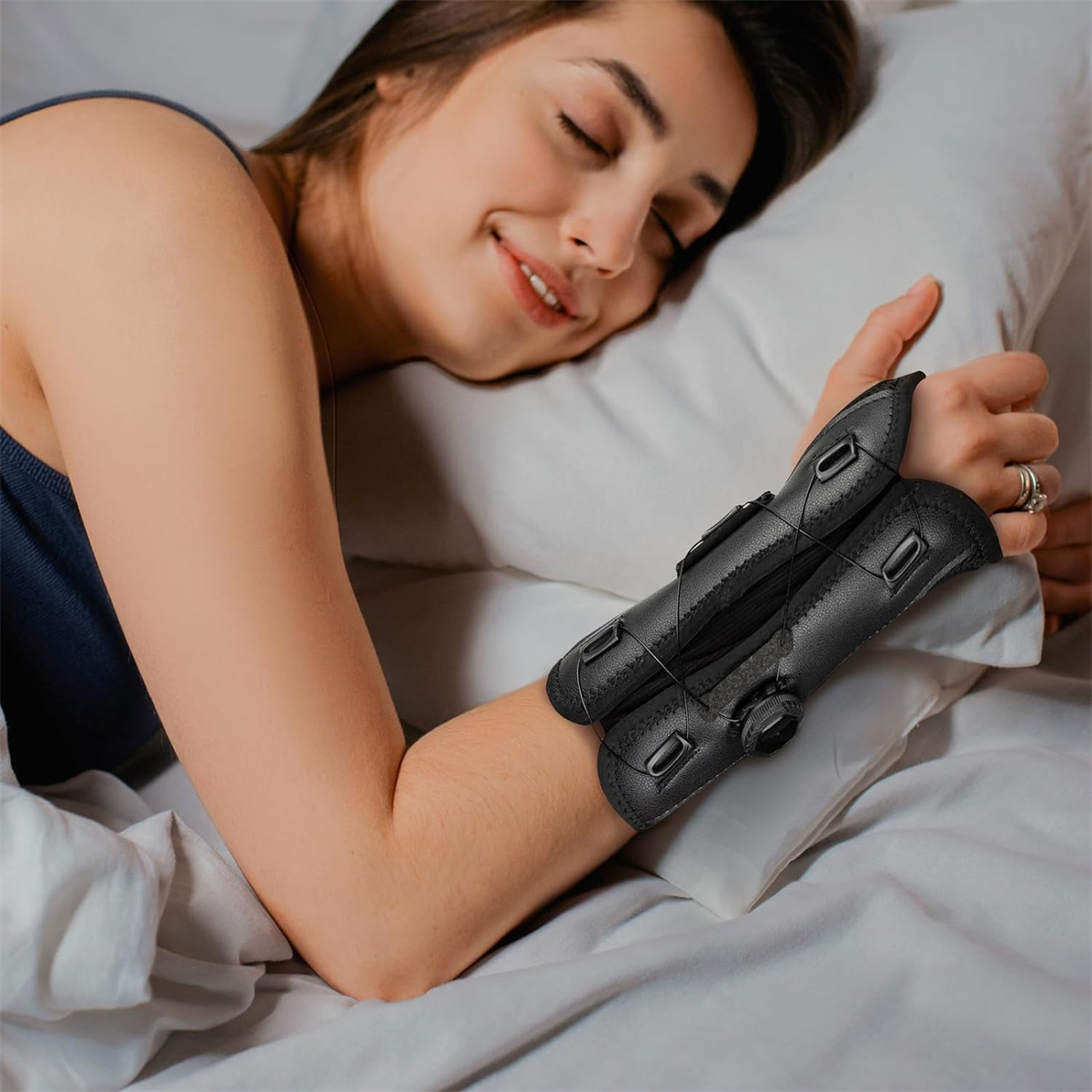 Eine Frau im Bett mit einer schwarzen Handgelenkstütze mit Drehknopf, auf einem Kissen liegend.