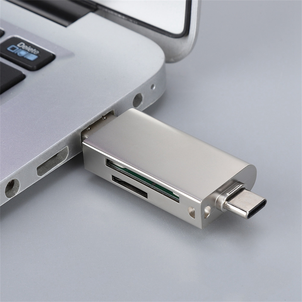 Silberner USB-C-Kartenleser, der an einen silbernen Laptop angeschlossen ist. Der Leser hat zwei Kartensteckplätze.