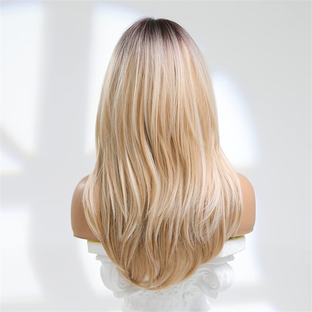Blonde Perücke auf einem weißen Schaufensterpuppenkopf. Dunkle Wurzeln, hellblondes Haar.