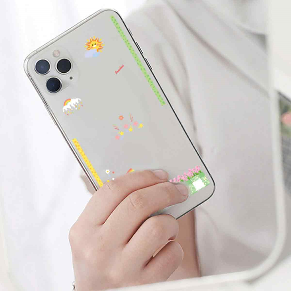Ein Smartphone mit Aufklebern von Sonne, Wolke, Regenbogen, Sternen und Blumen auf der Rückseite.